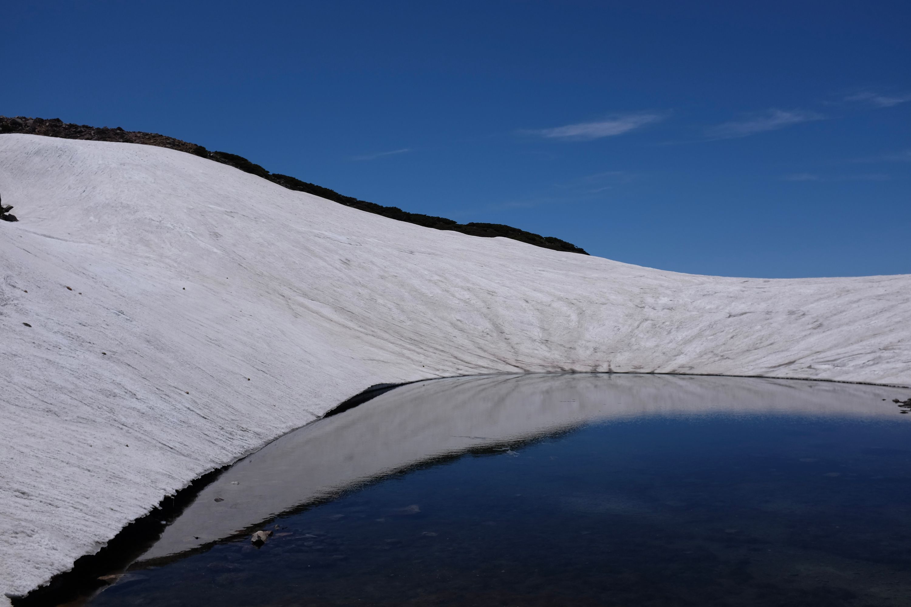 One of the small crater lakes immediately below the Gozengamine summit of Hakusan, its sides completely covered in snow.