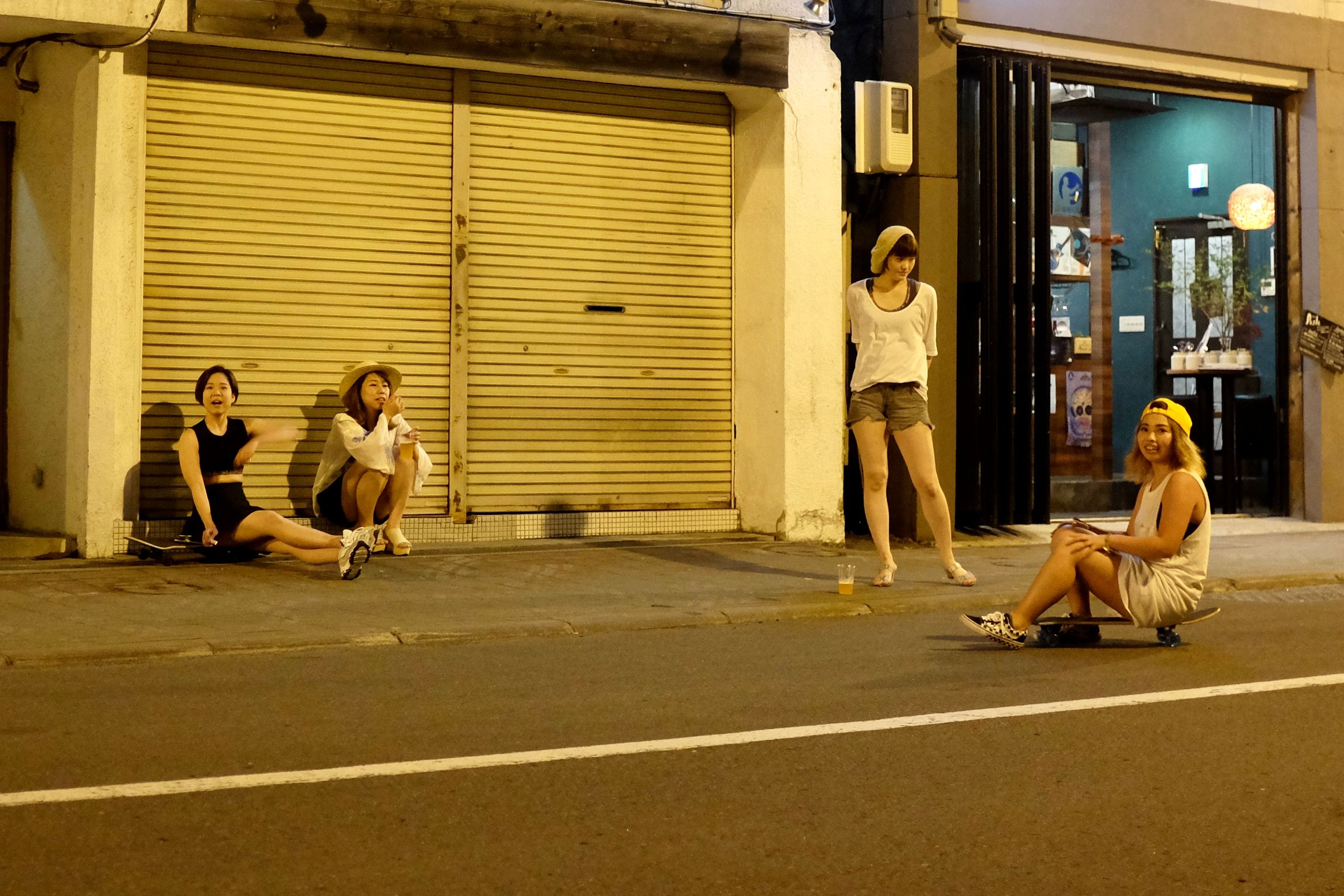 Four girls hang out on a street, two of them looking into the camera.