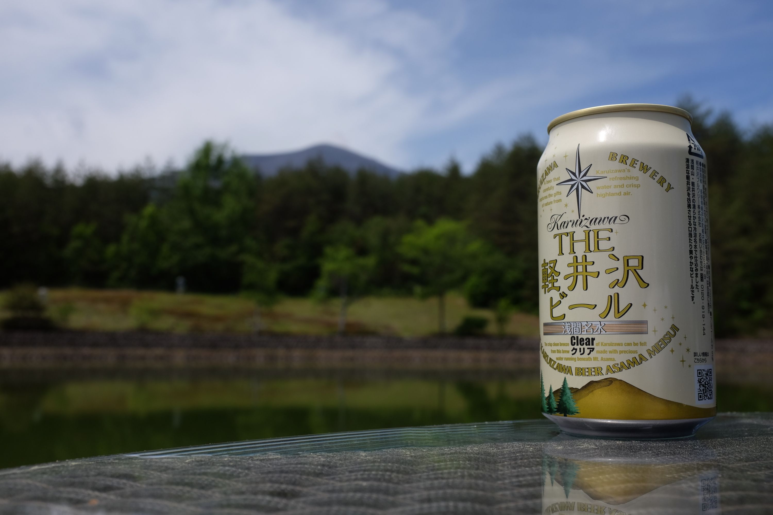 A can of beer showing Mount Asama with the actual Mount Asama on the horizon.