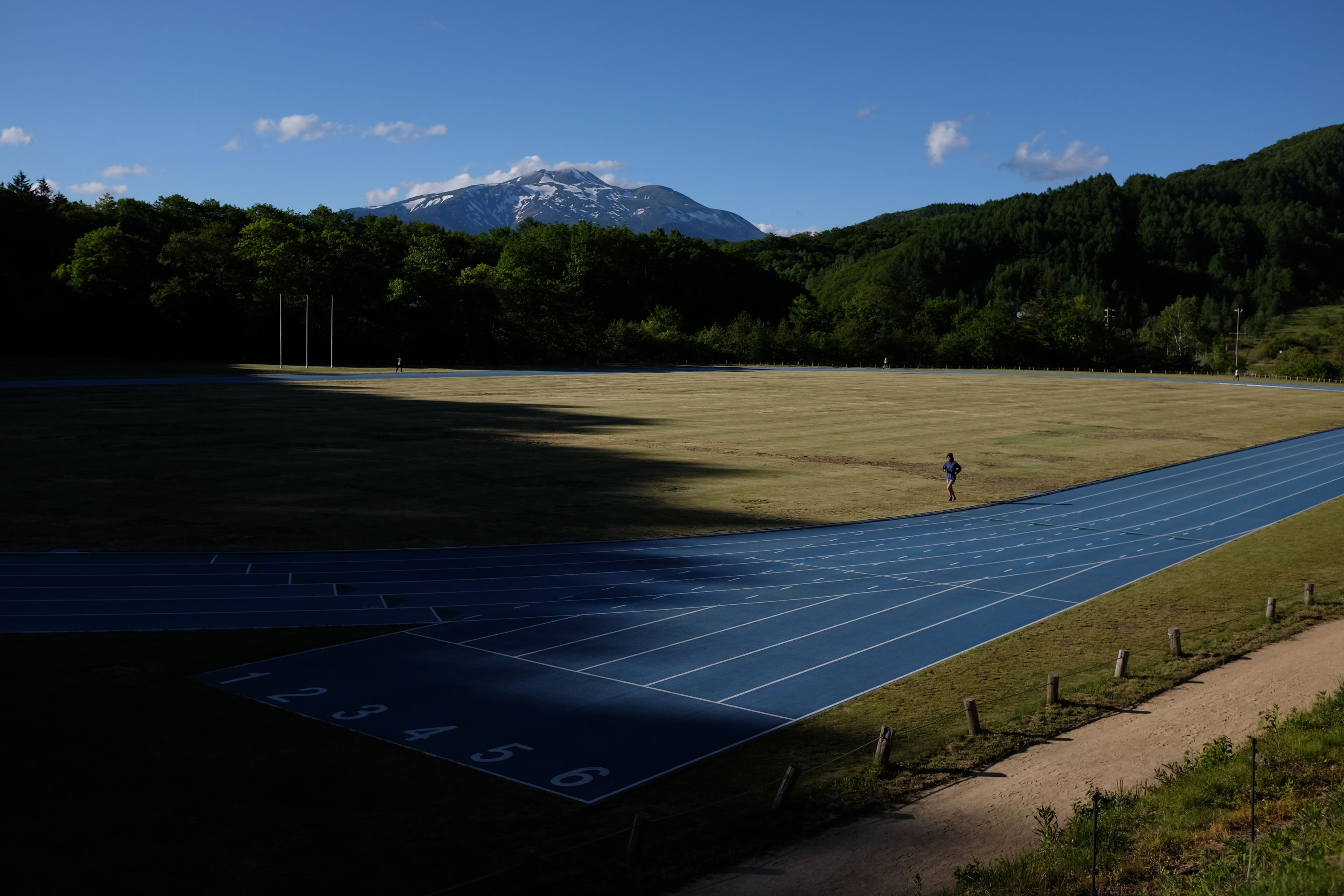 Running track in the late afternoon light, with Mount Norikura on the horizon.