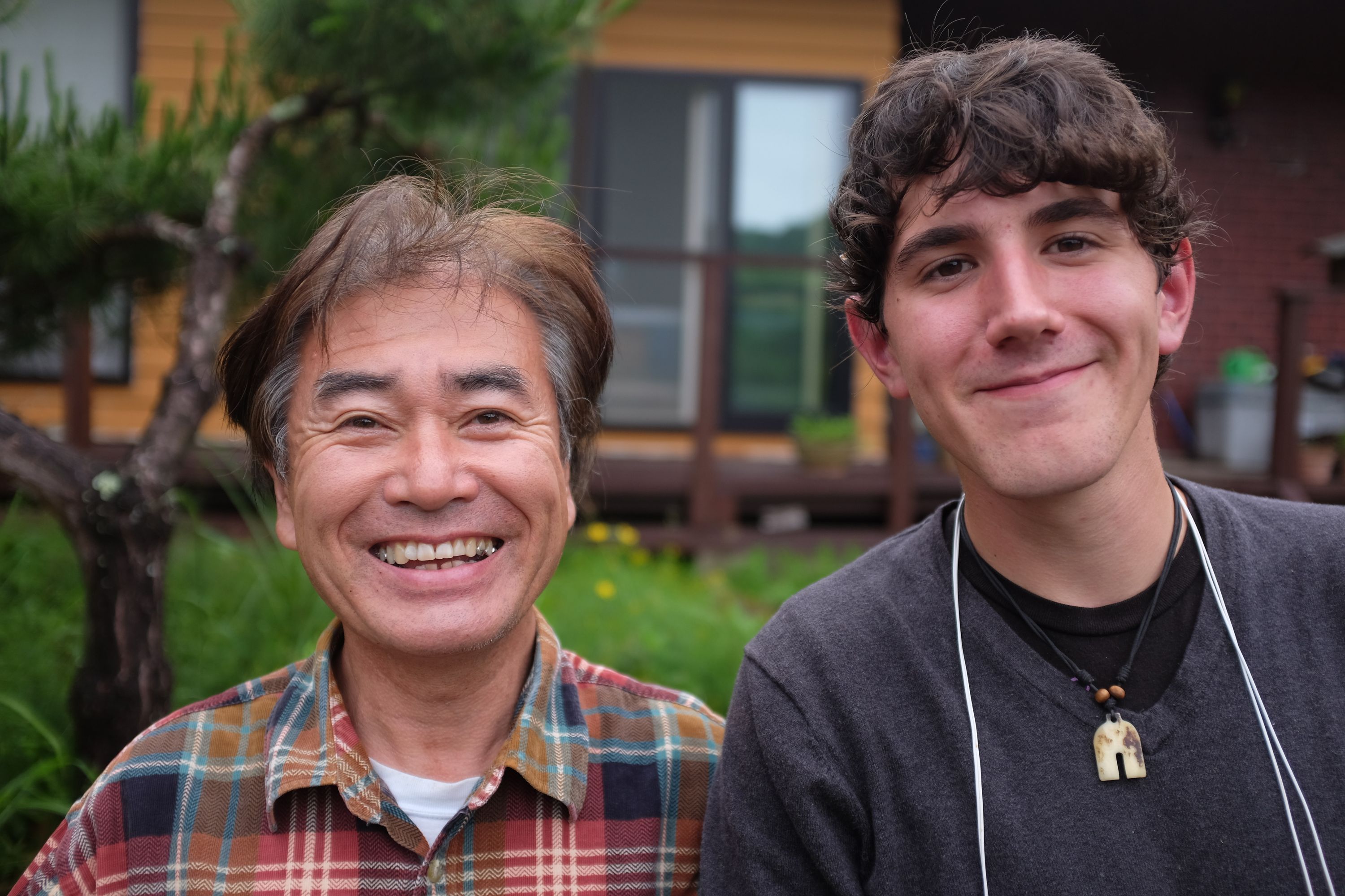 A Japanese man and an American boy smile into the camera.
