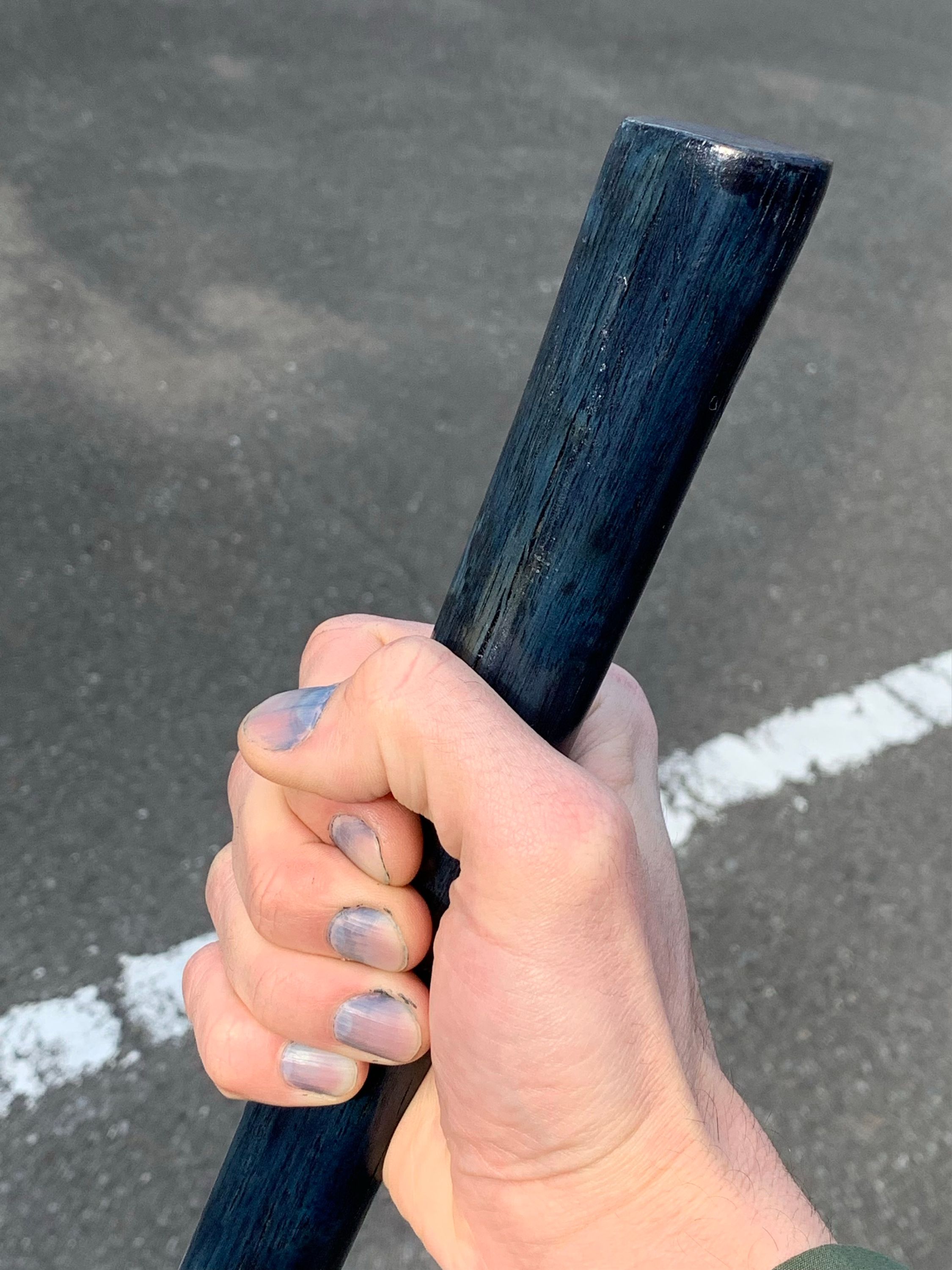 A hand with blue fingernails, dyed with indigo die, holds an indigo blue walking stick.