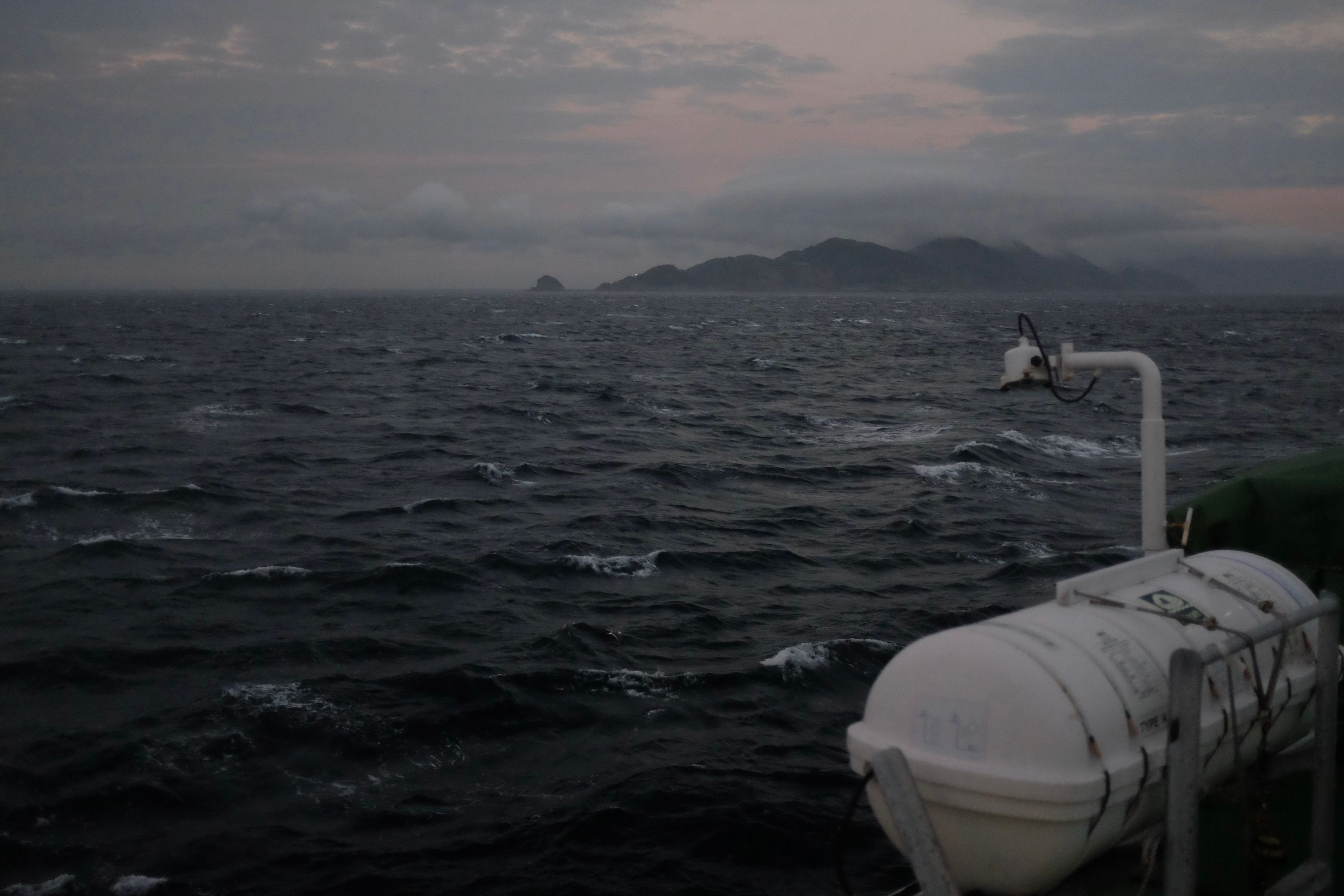 Looking at an island of jagged mountains across a grey, choppy sea from the ferry.