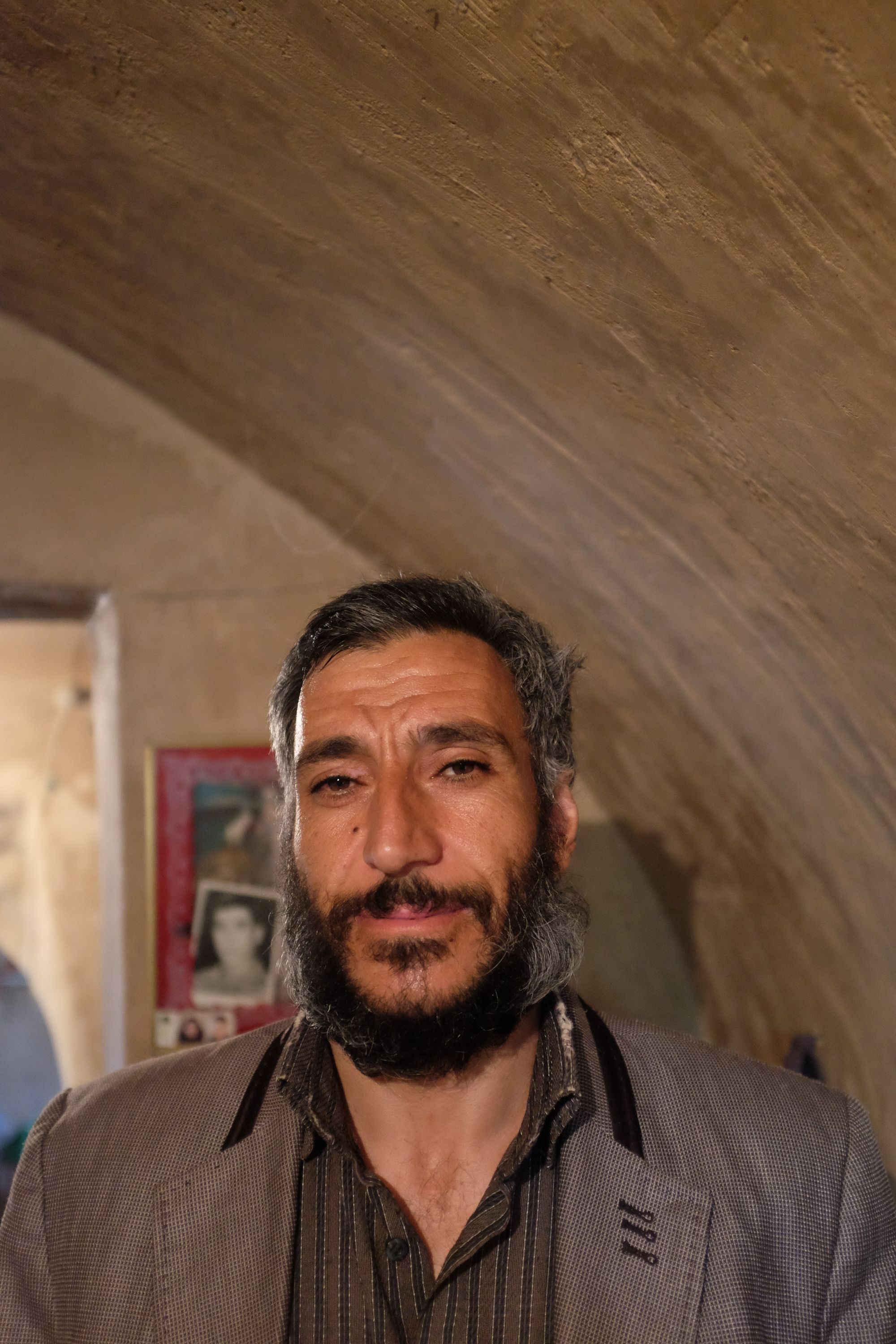 A bearded man smiles into the camera under an arched ceiling.