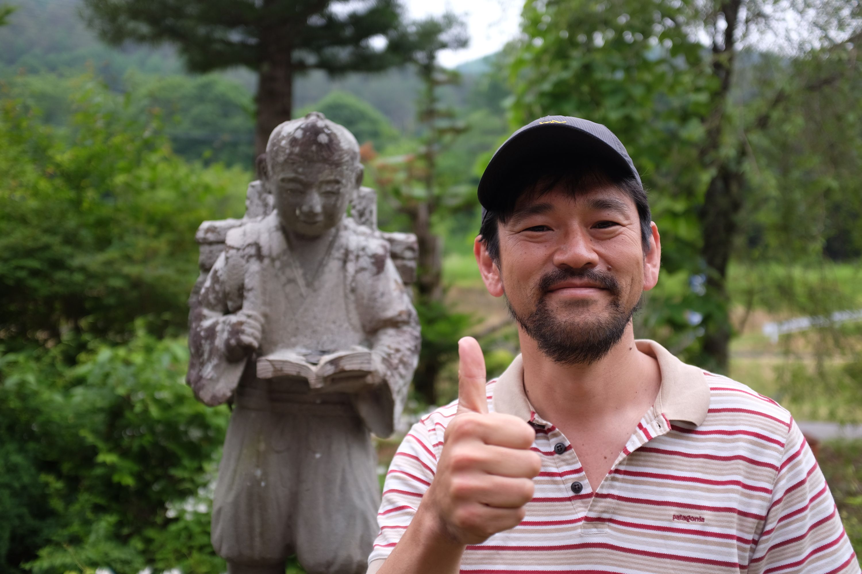 A Japanese man, Kuroiwa Naoki, gives a thumbs up with his right hand.