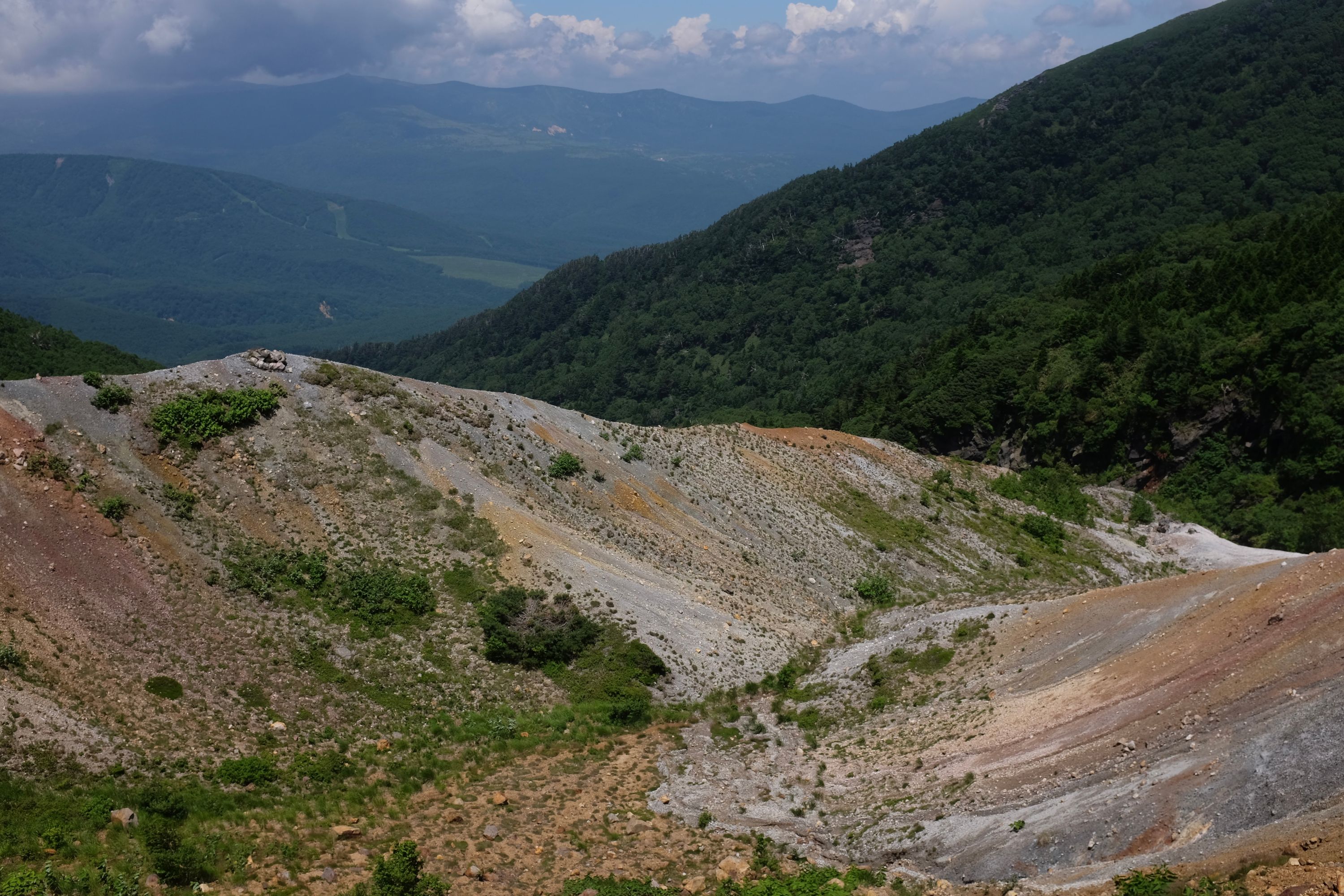 Colorful slopes of volcanic scree slope towards a valley.