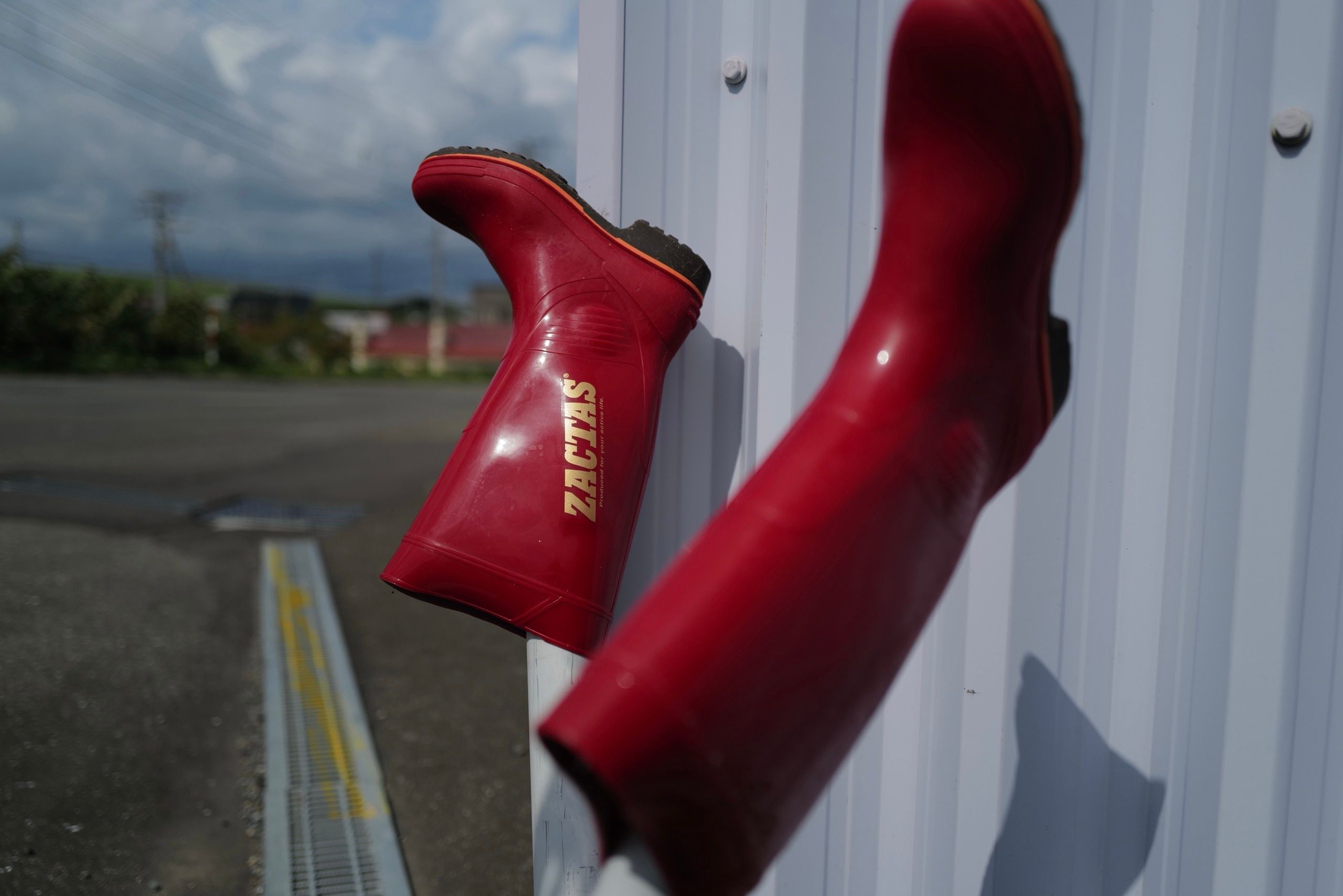 A pair of red rubber boots drying in the sun