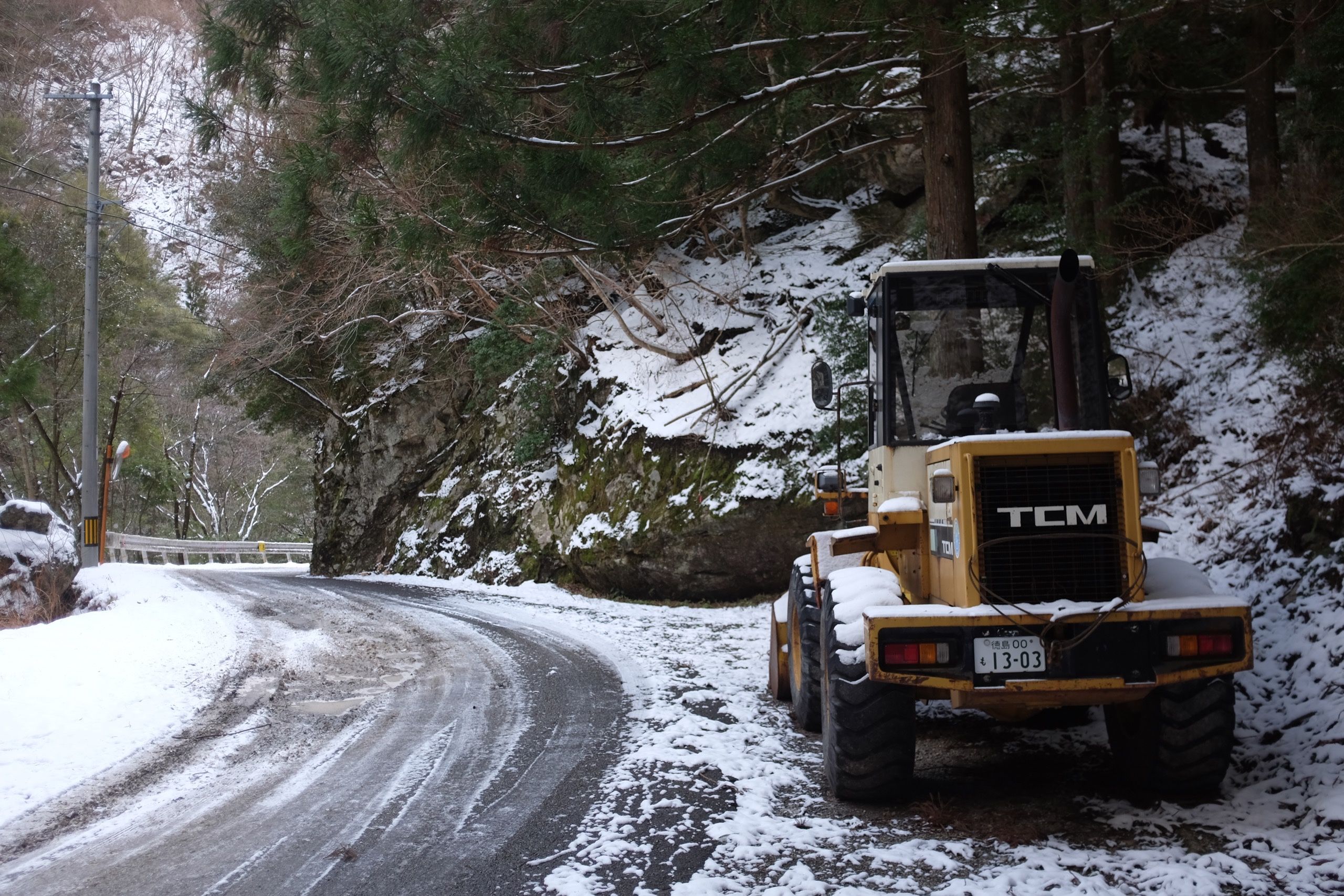 A bulldozer stands in the snow on a forest road.