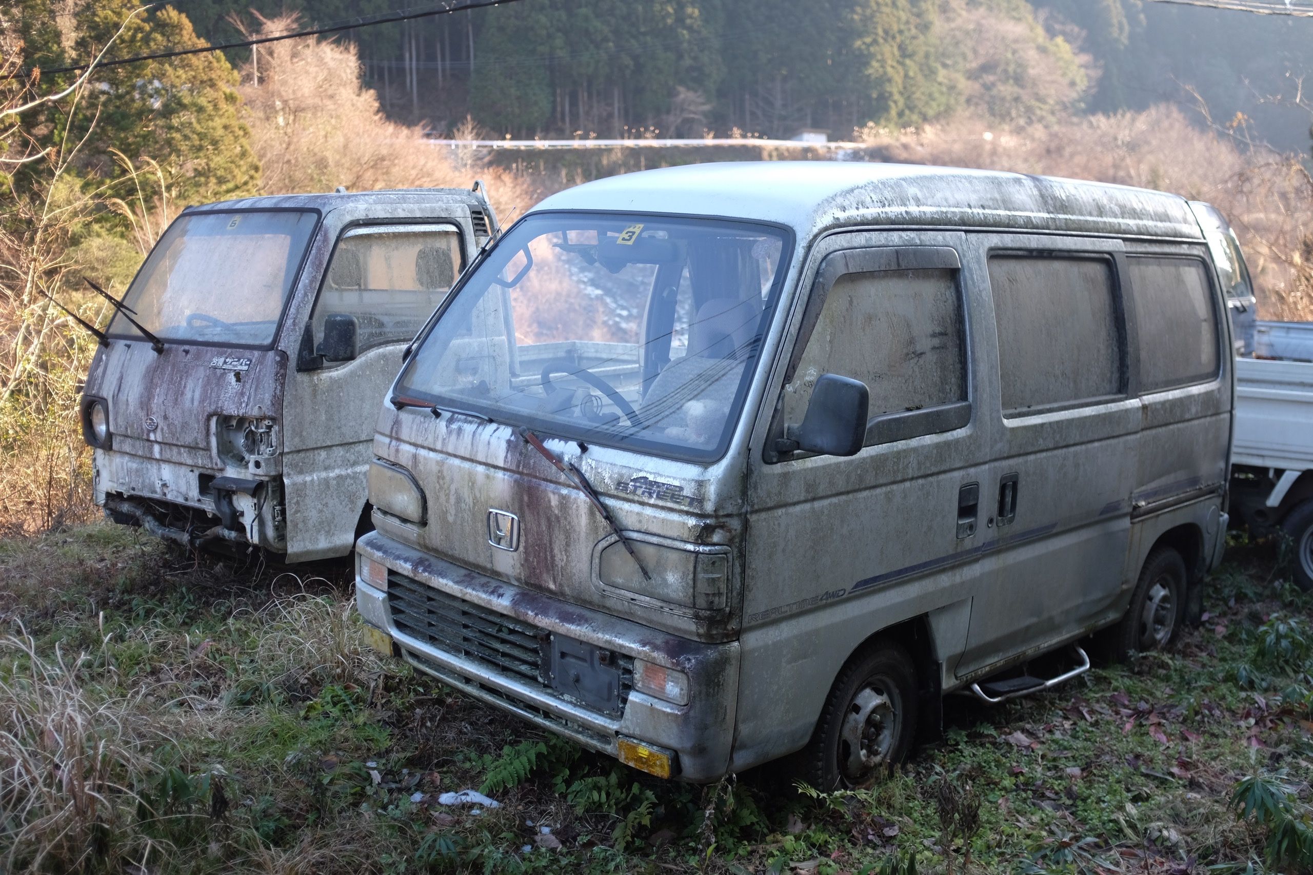 Two dilapidated microvans by the side of the road in beautiful afternoon sunlight.