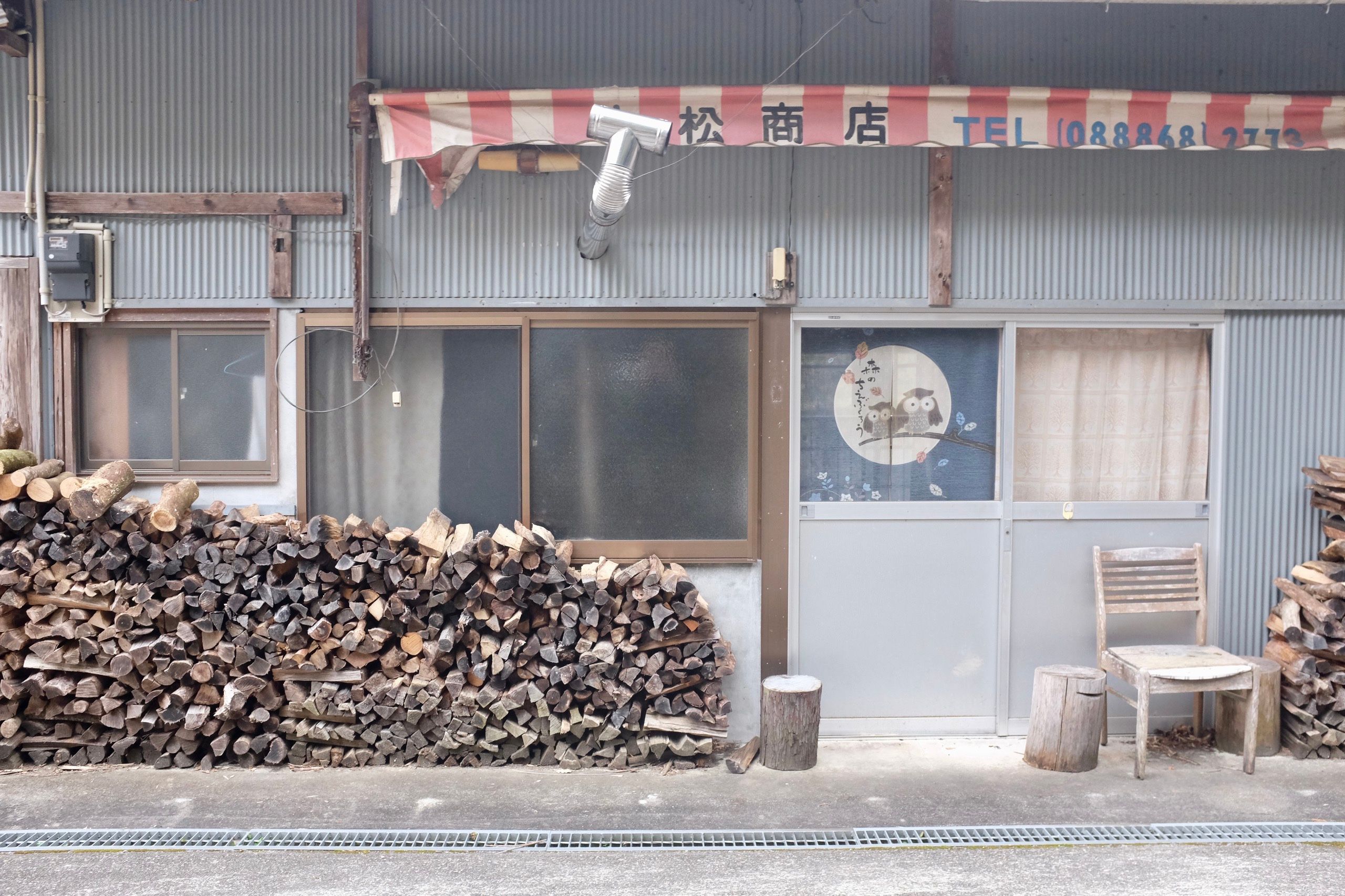 A heap of firewood in front of a shop.