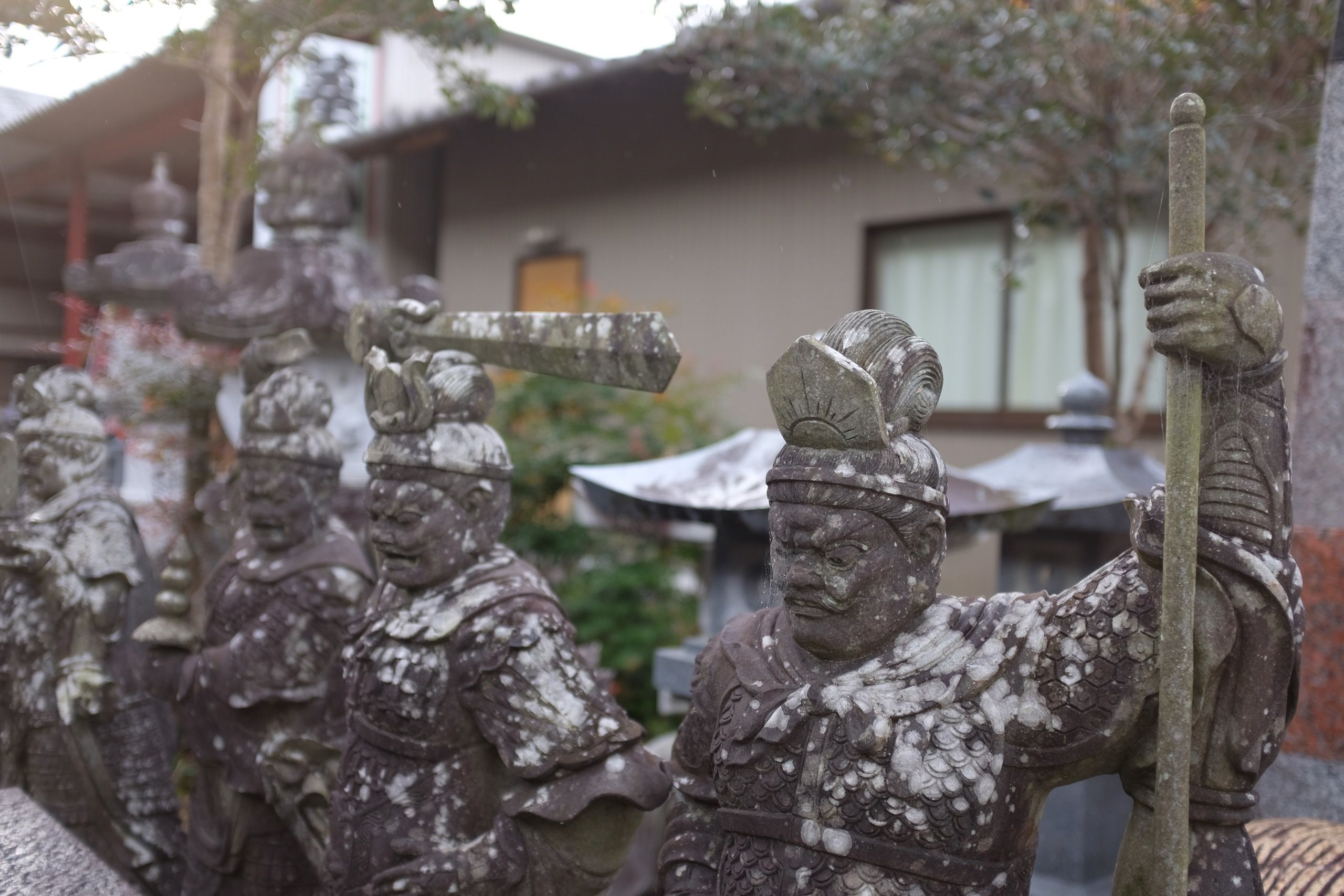 Carved stone warriors covered in lichen.