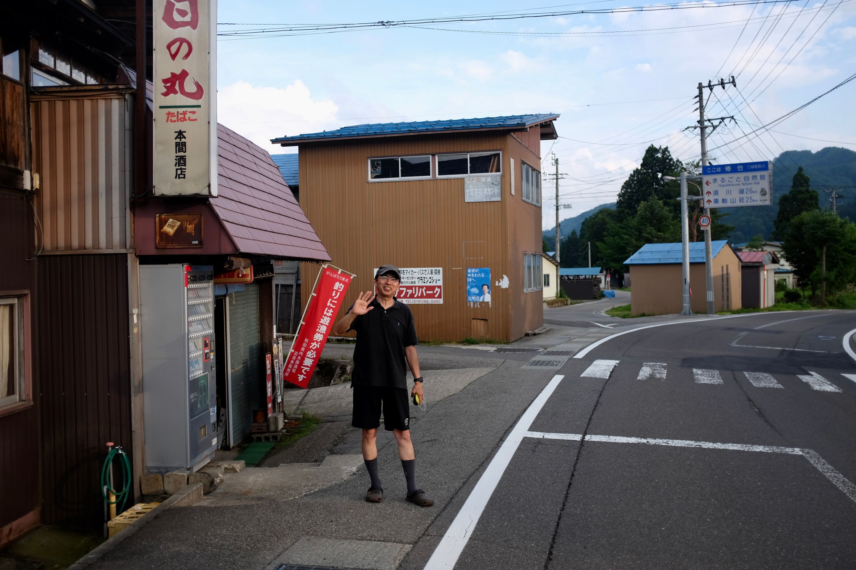 Mr. Tadashi waves goodbye in front of his store.