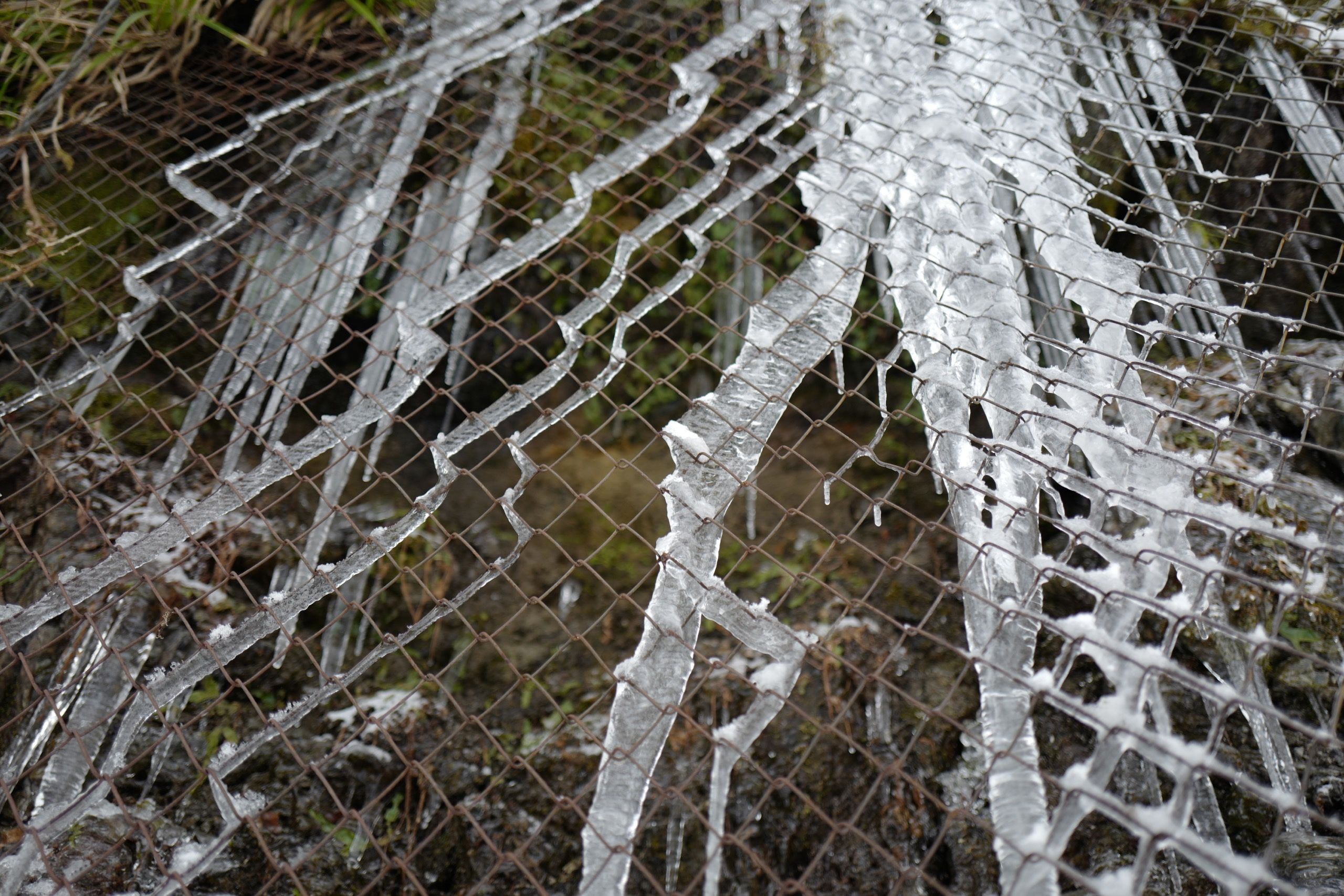 Icicles form zigzag shapes on a chain-link fence.