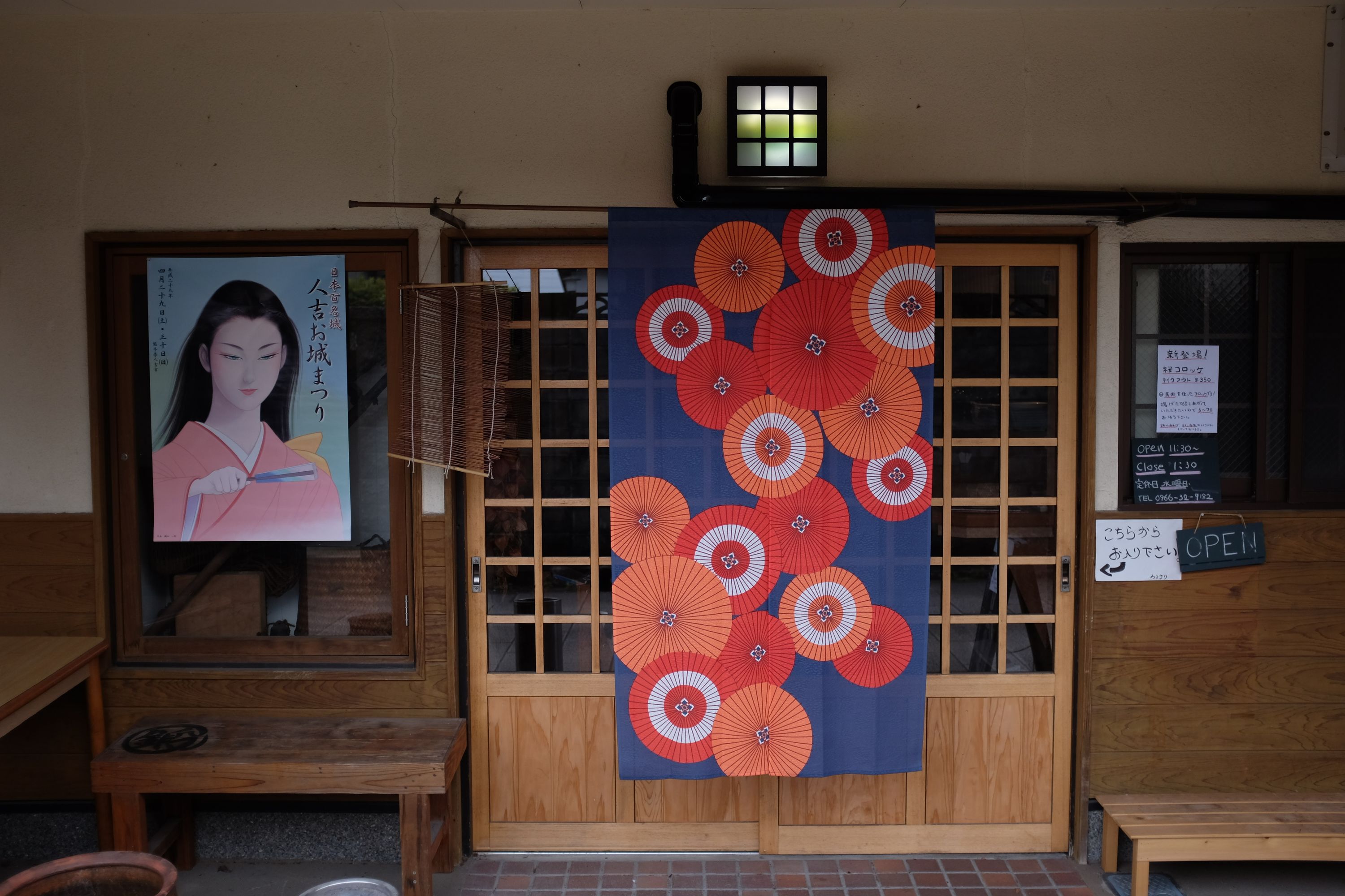 The sliding door of a Japanese restaurant, decorated with colorful circular motifs and a poster of a woman in a pink dress.