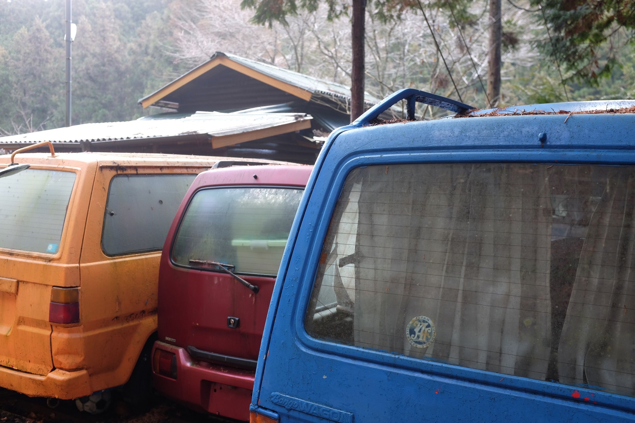 An orange, a red, and a blue microvan parked next to each other.