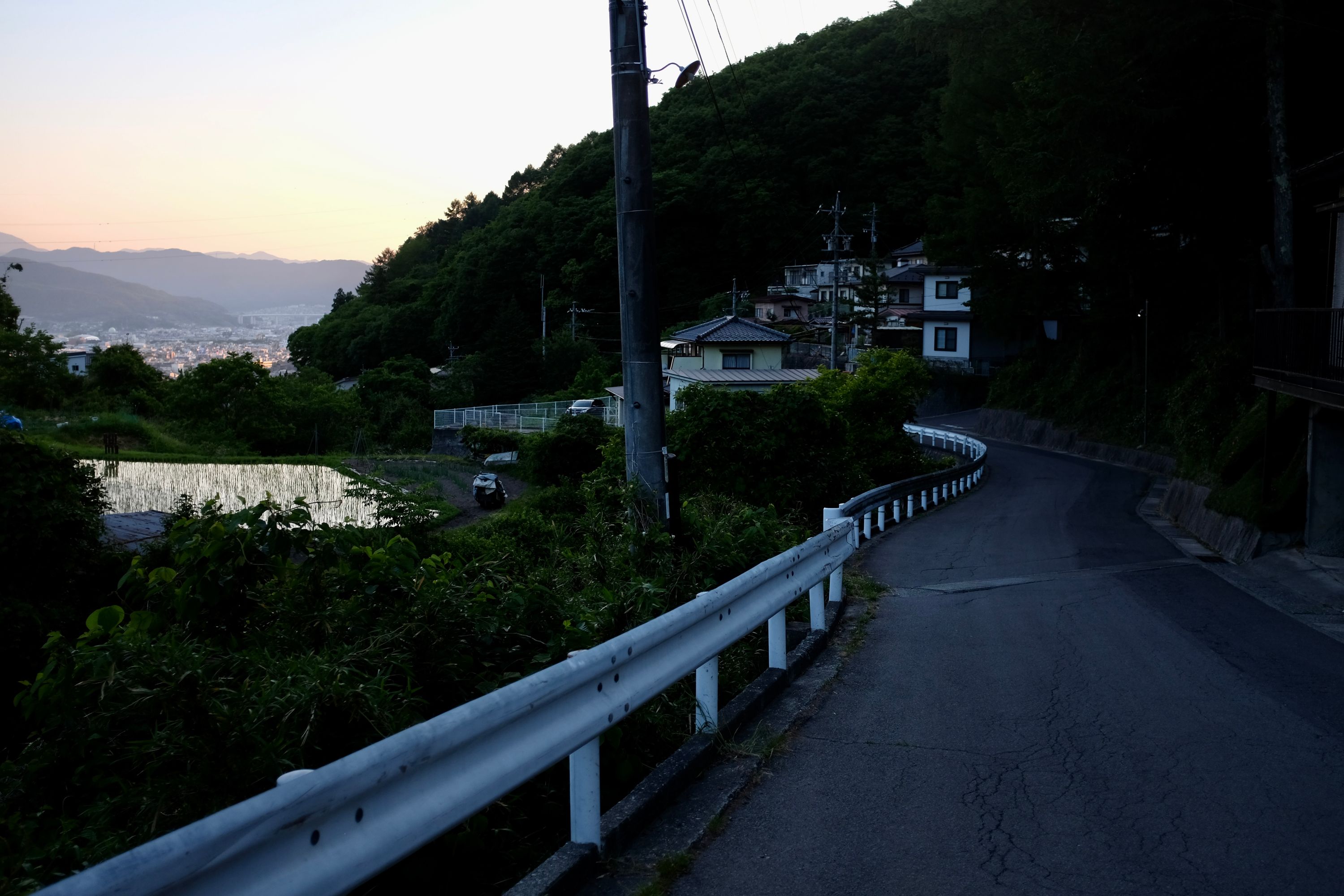 Looking down on a twisting road, village houses, ricefields, and mountains on the horizon.