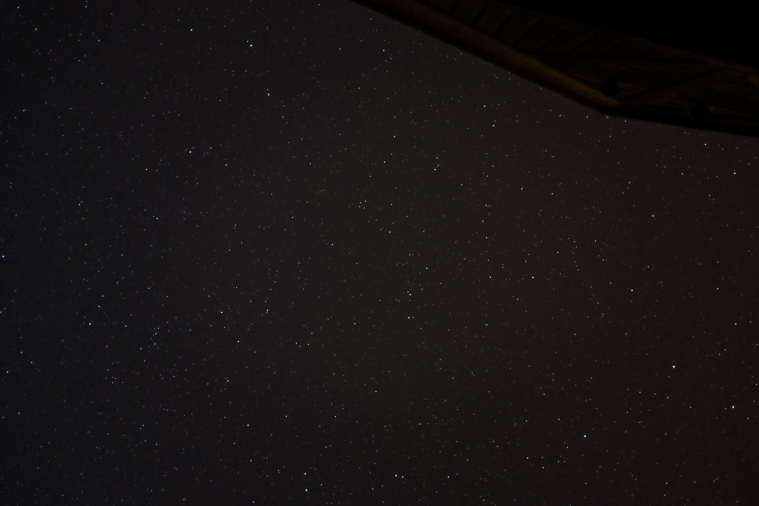 Looking up at the night sky, full of stars, from what appears to be the porch of a house.