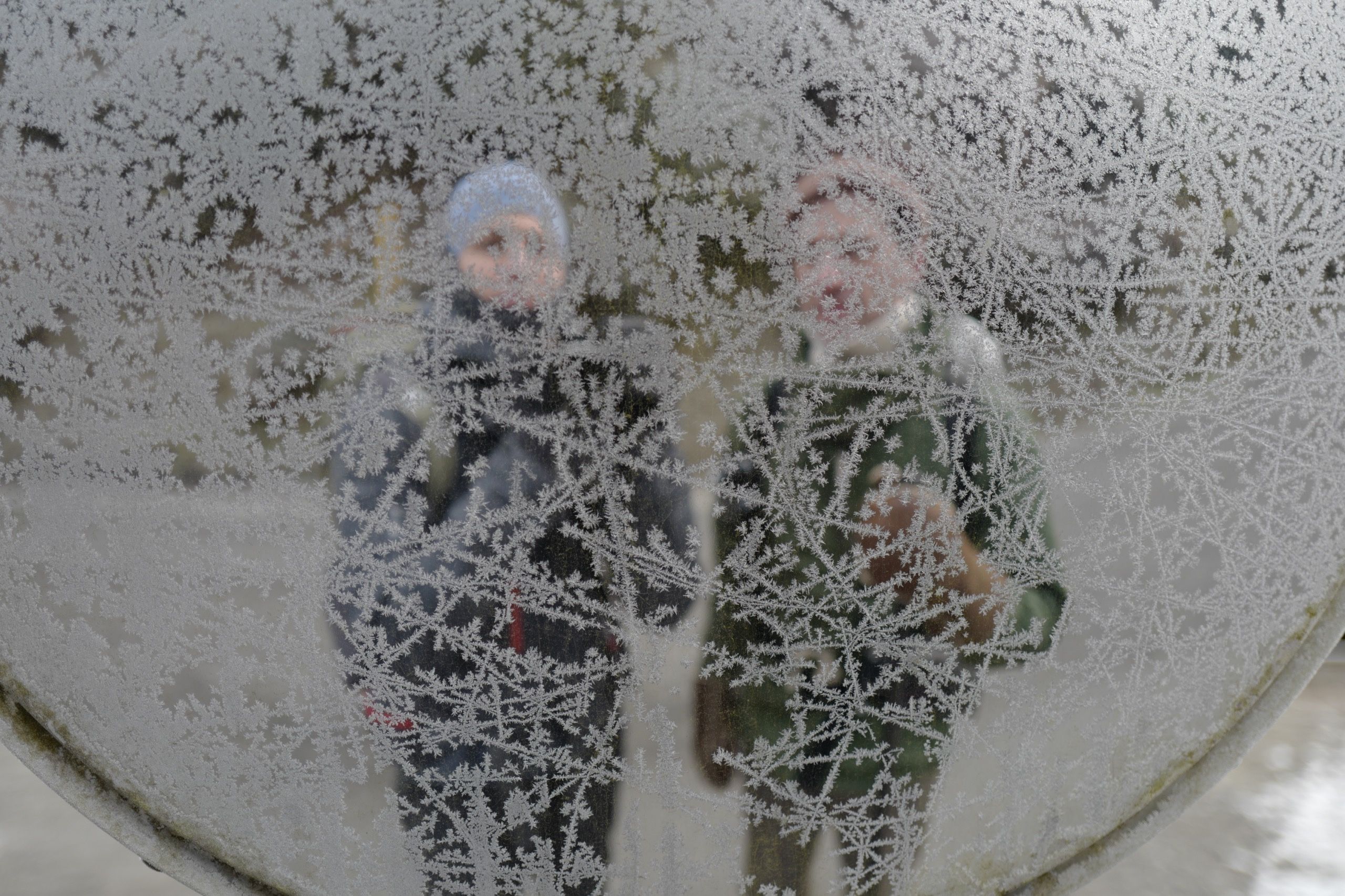 The silhouettes of two people, the author and Gyula Simonyi, reflected in a traffic mirror criss-crossed with frost.