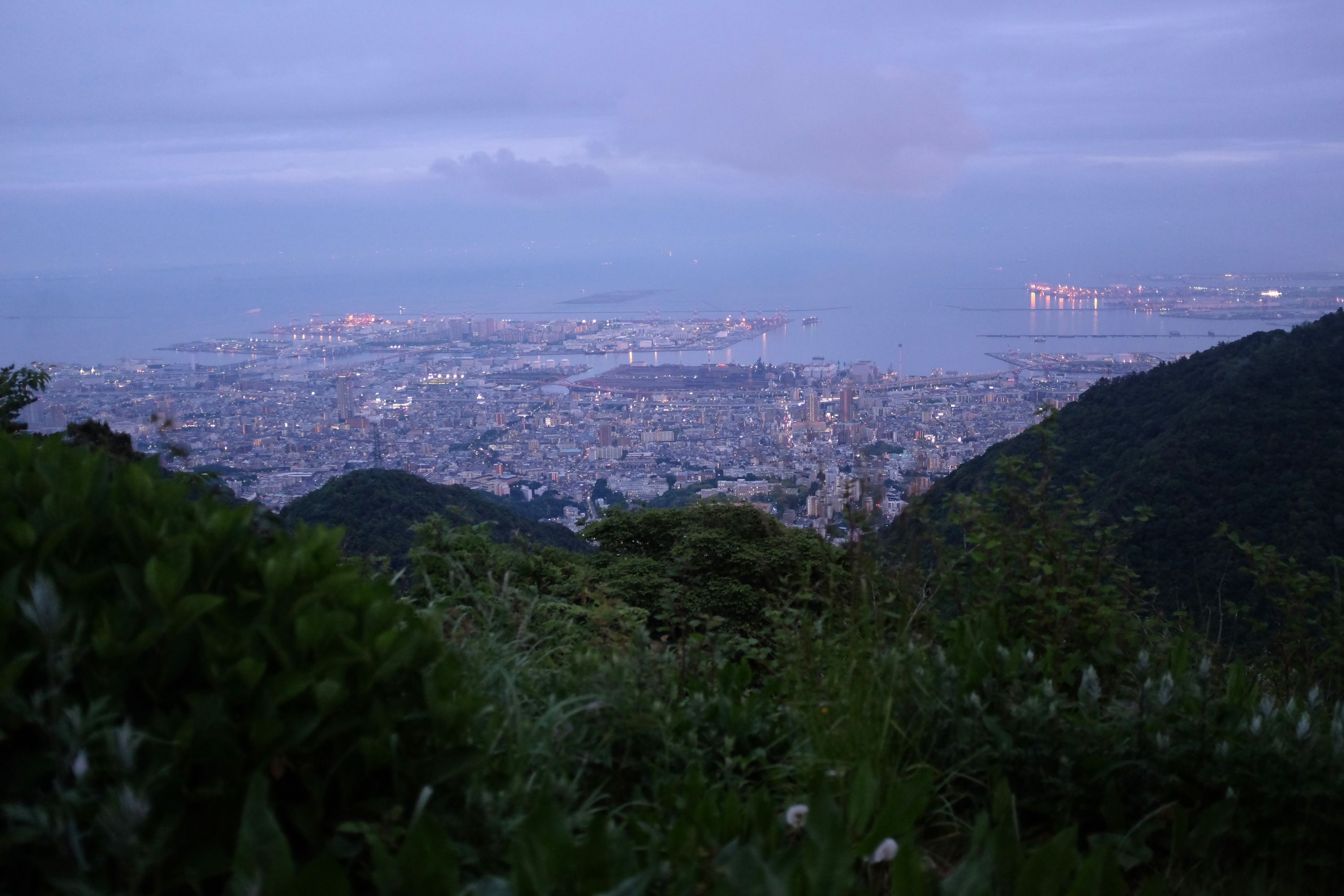 A similar view taken about an hour later and from a higher point, with some of the lights of the city already on.