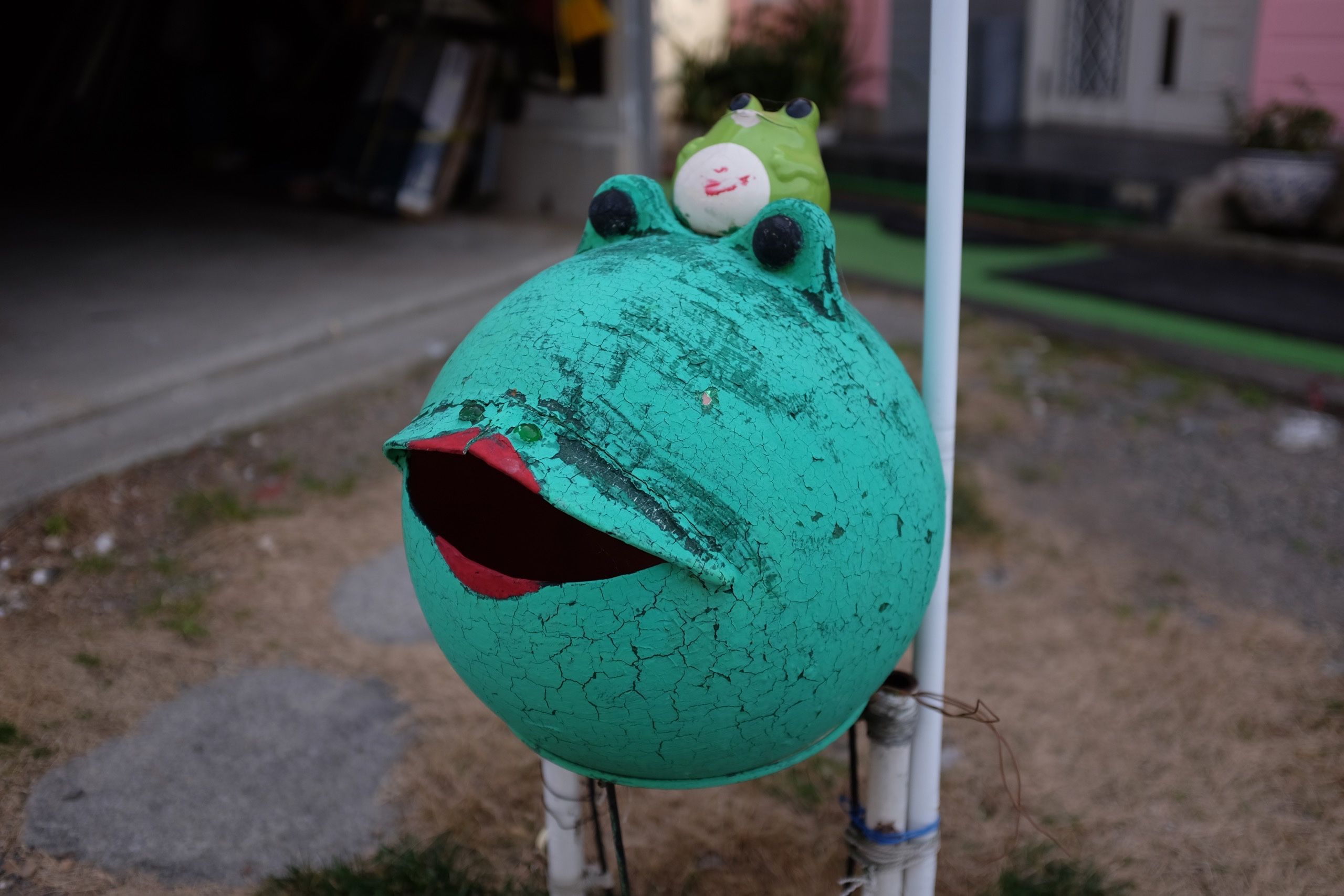 An old buoy painted to look like a frog wearing red lipstick.