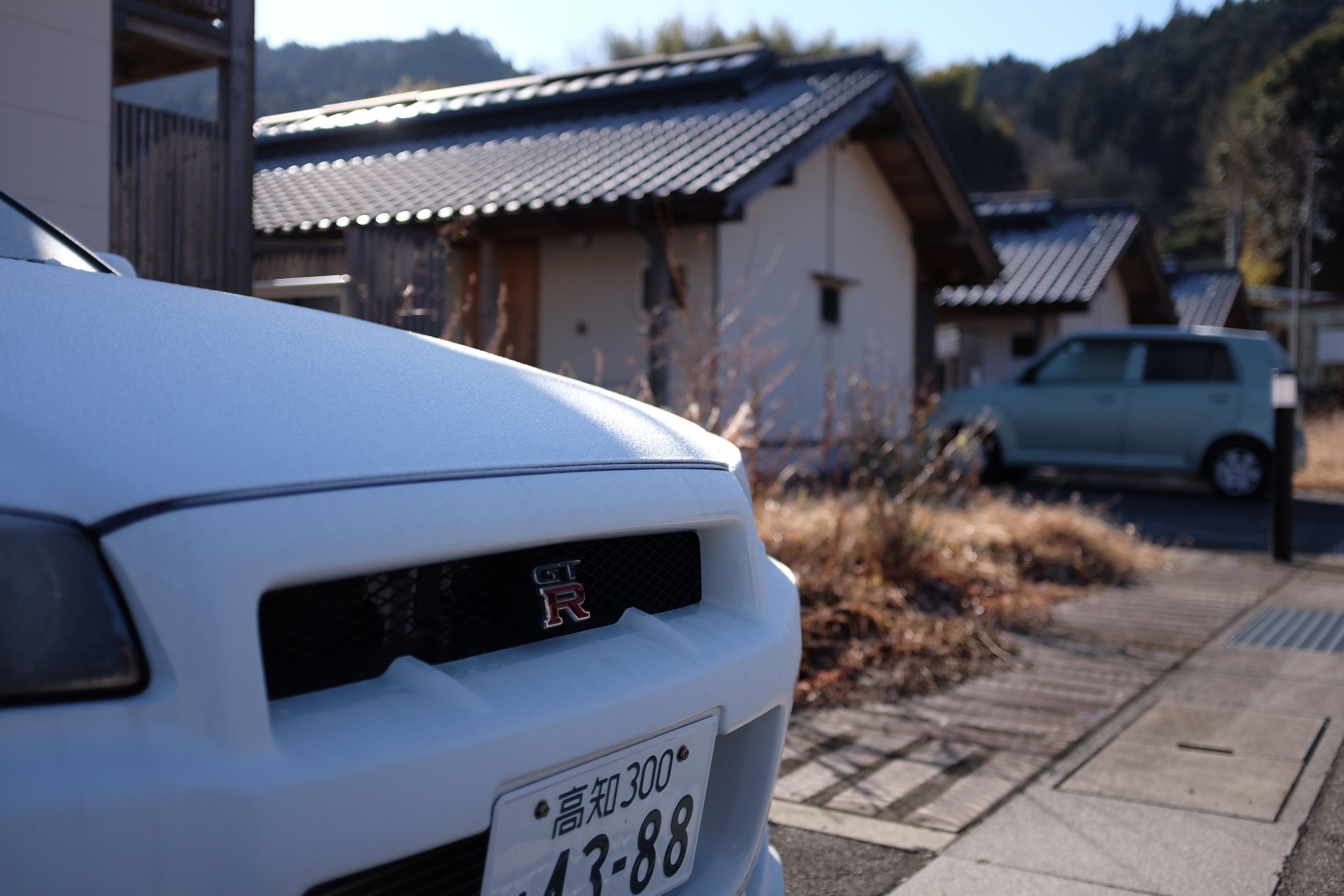 The frozen hood of a white Nissan GT-R on a sunny winter morning.