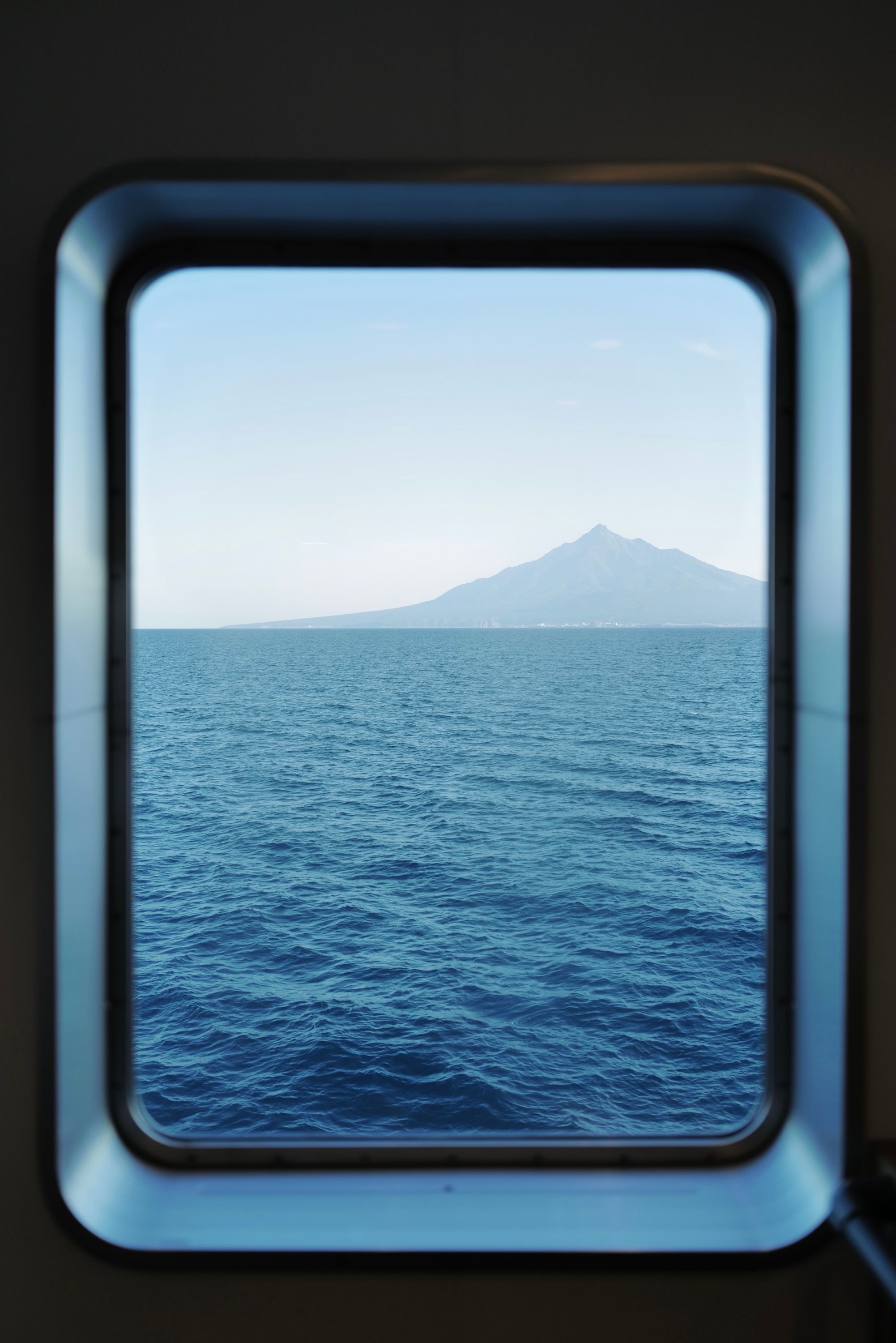 Mount Rishiri seen across the water through the window of a ferry