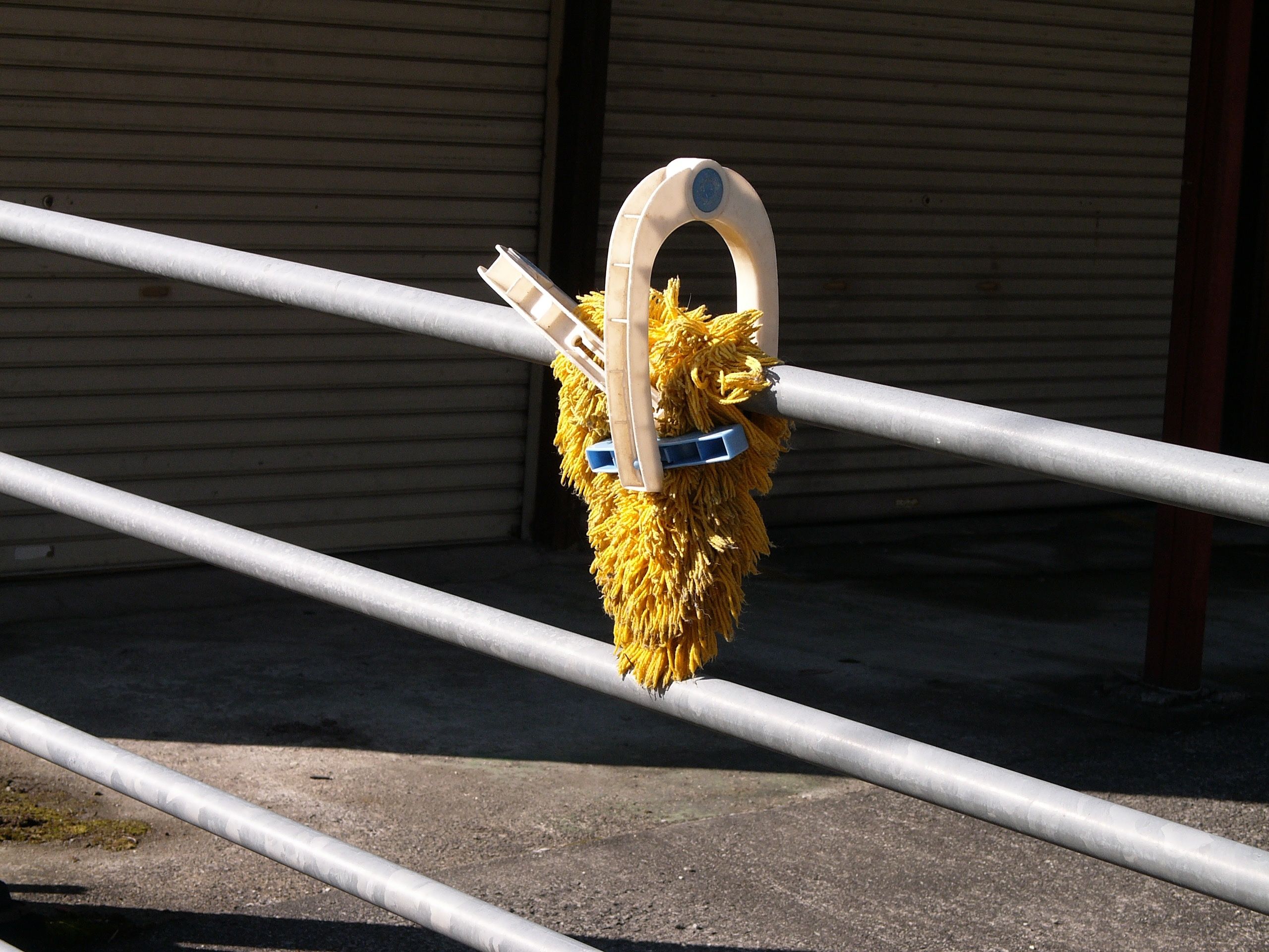 A mop that looks like a wild mask drying on a fence.