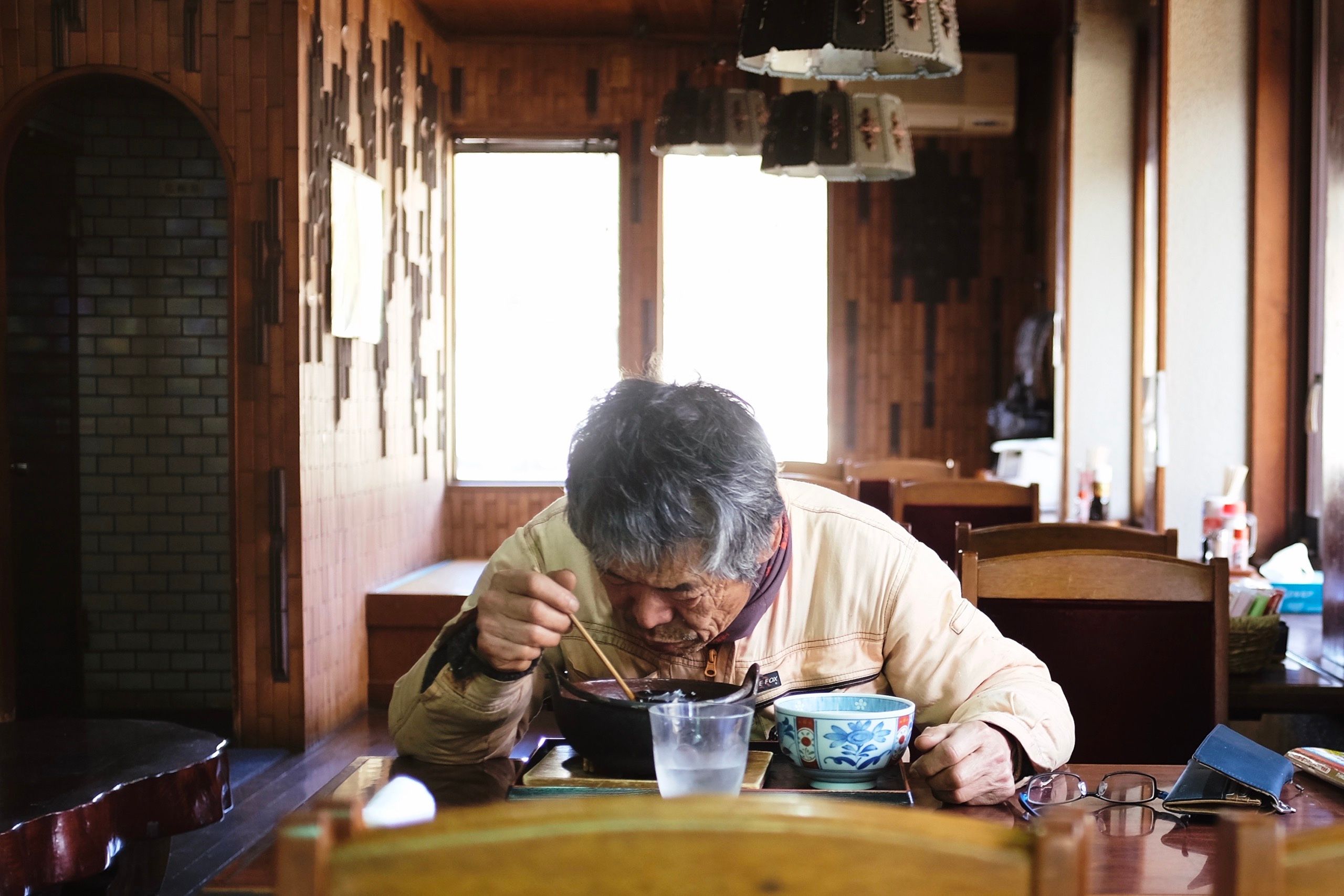 A man in workmen’s overalls eats a bowl of the noodles.