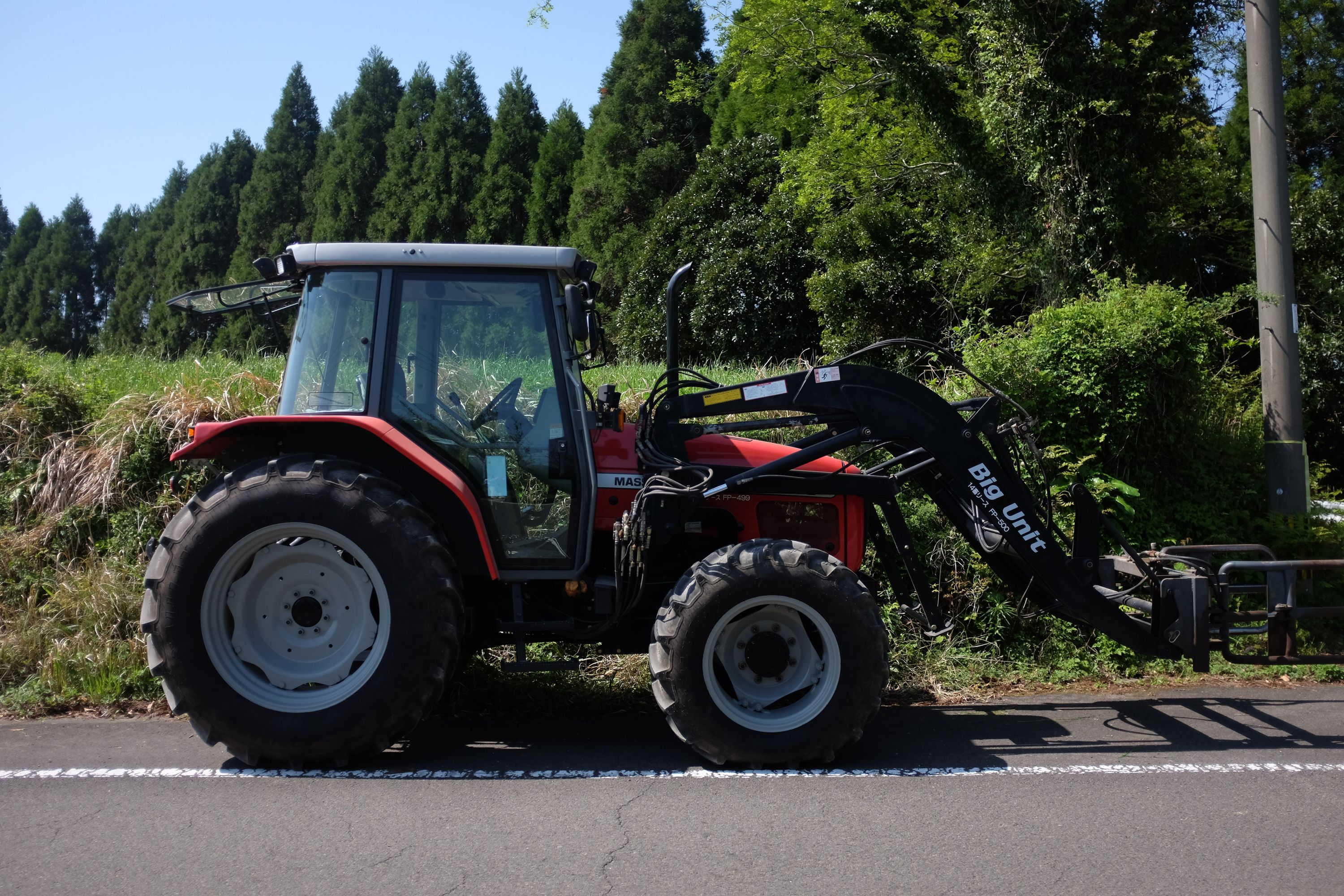 A tractor with a forklift labelled Big Unit stands by the side of the road.