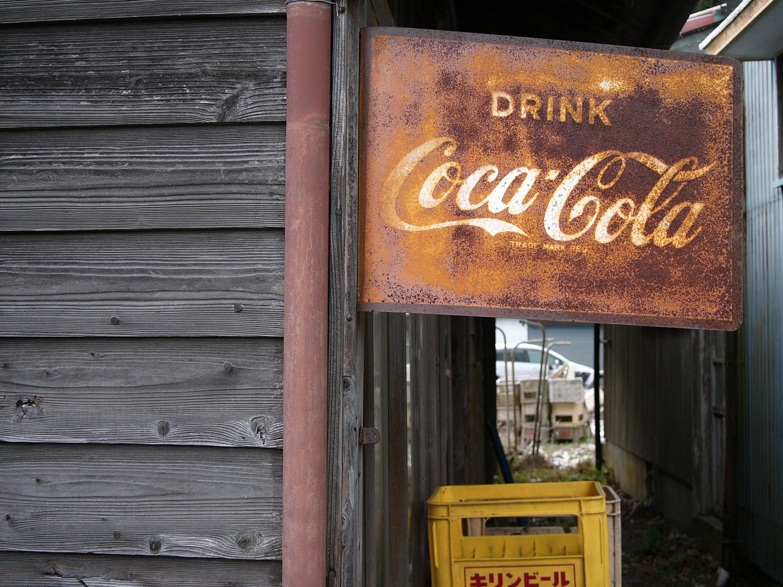 A rusty Coca-Coca sign affixed to a shed.