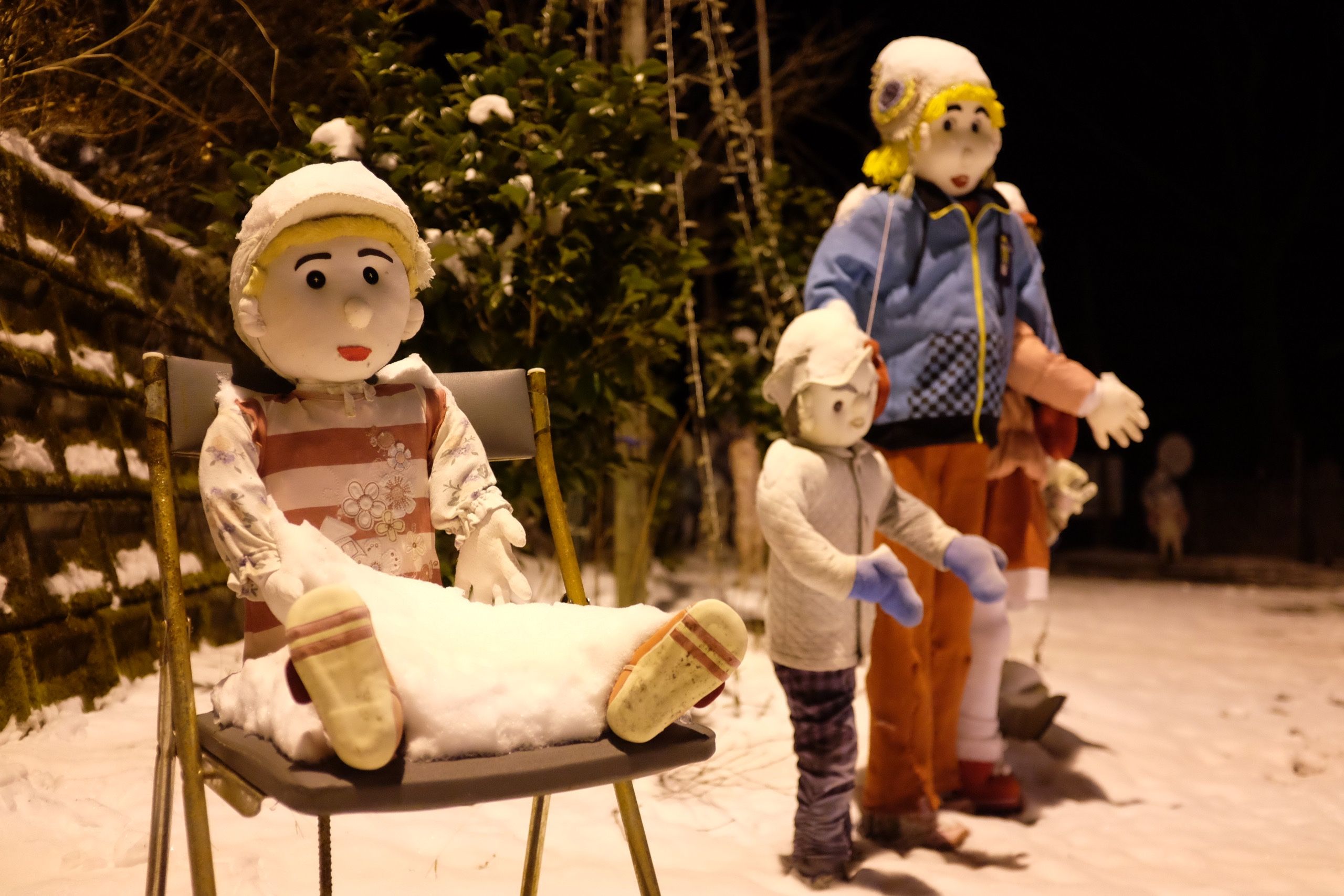Closeup of some of the dolls, looking cheerful but covered in snow.