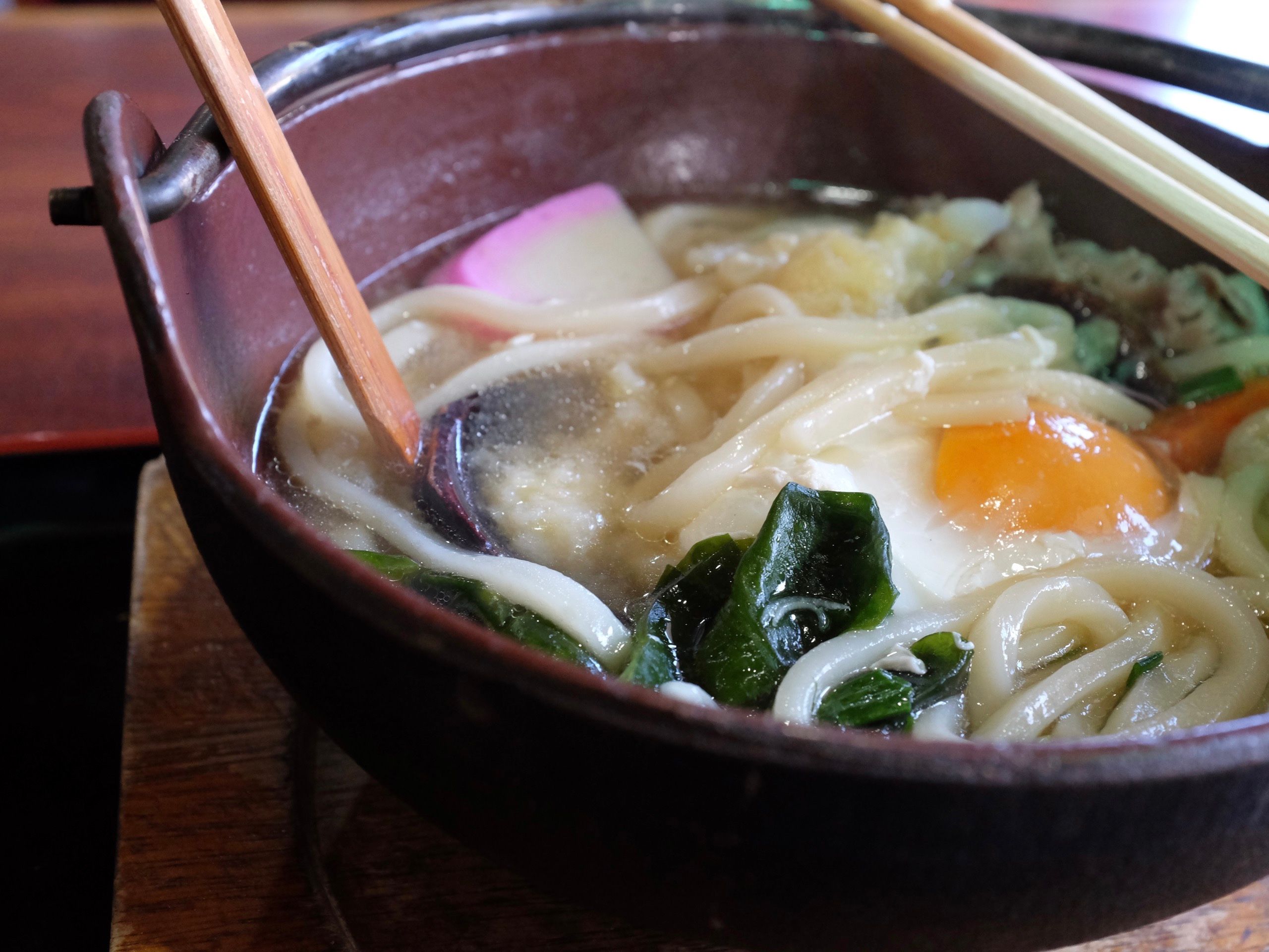 A bowl of noodles with vegetables and an egg.