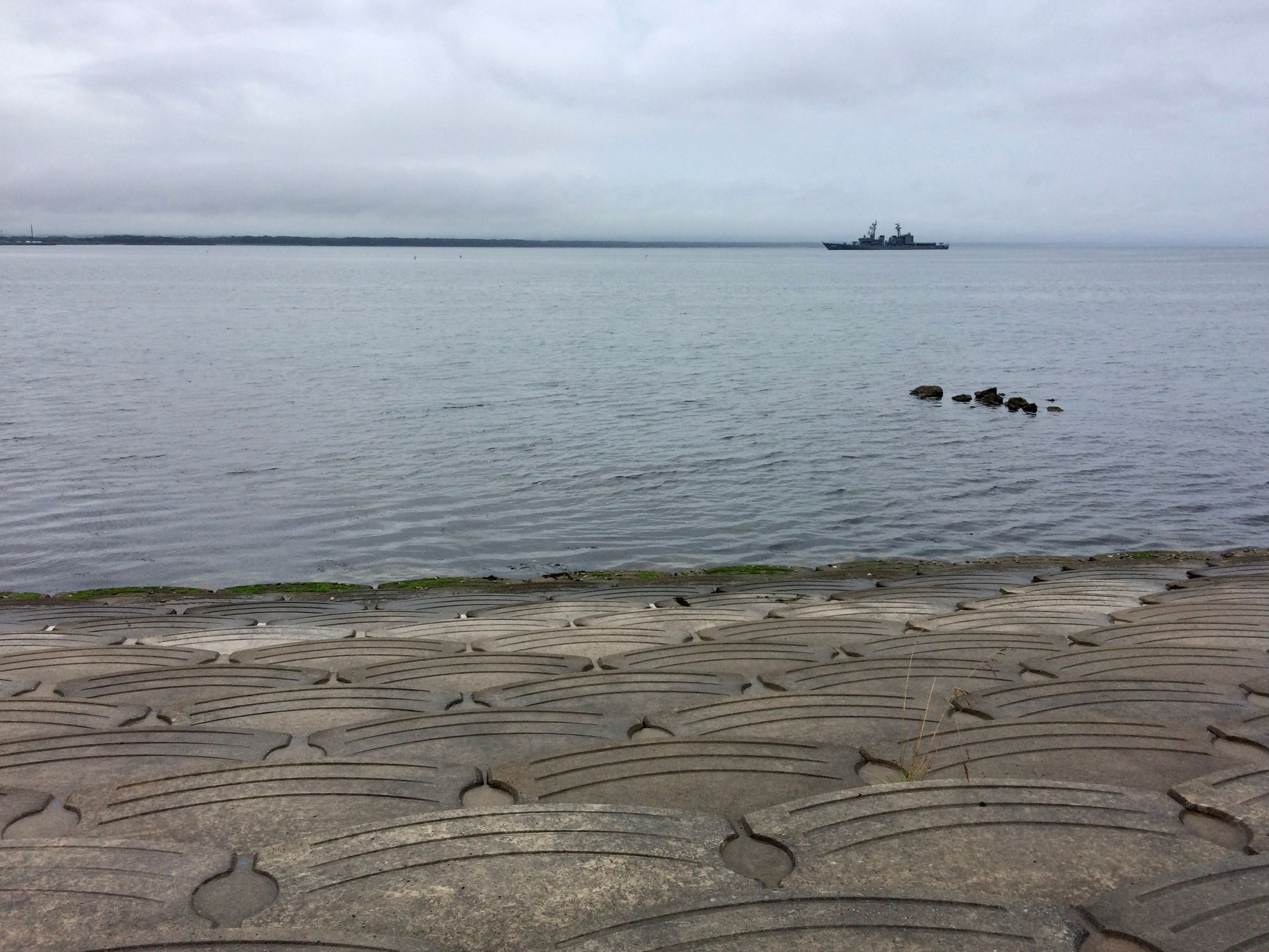 A battleship floats on the sea in the distance.