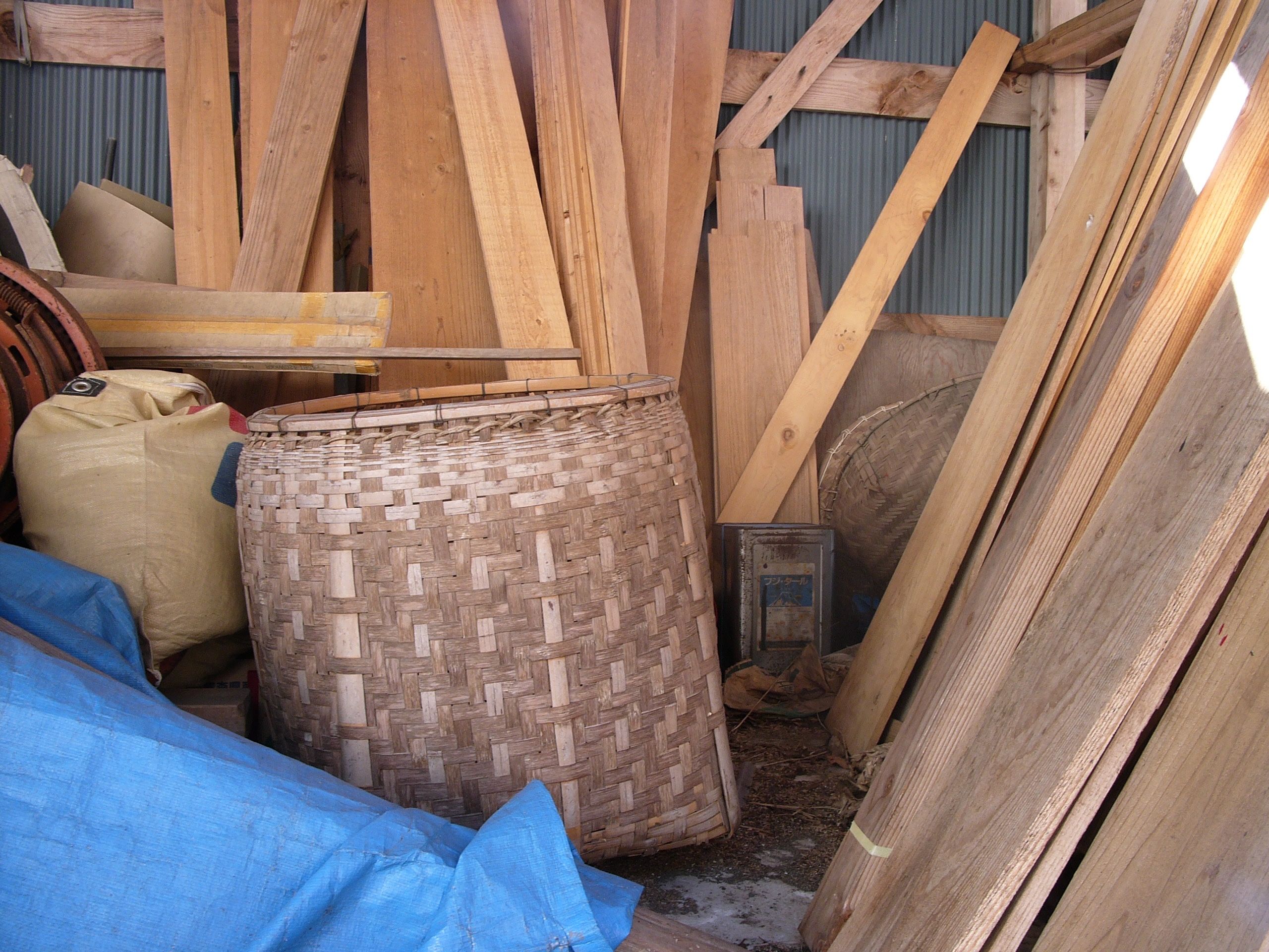A woven basket and some planks in a shed.