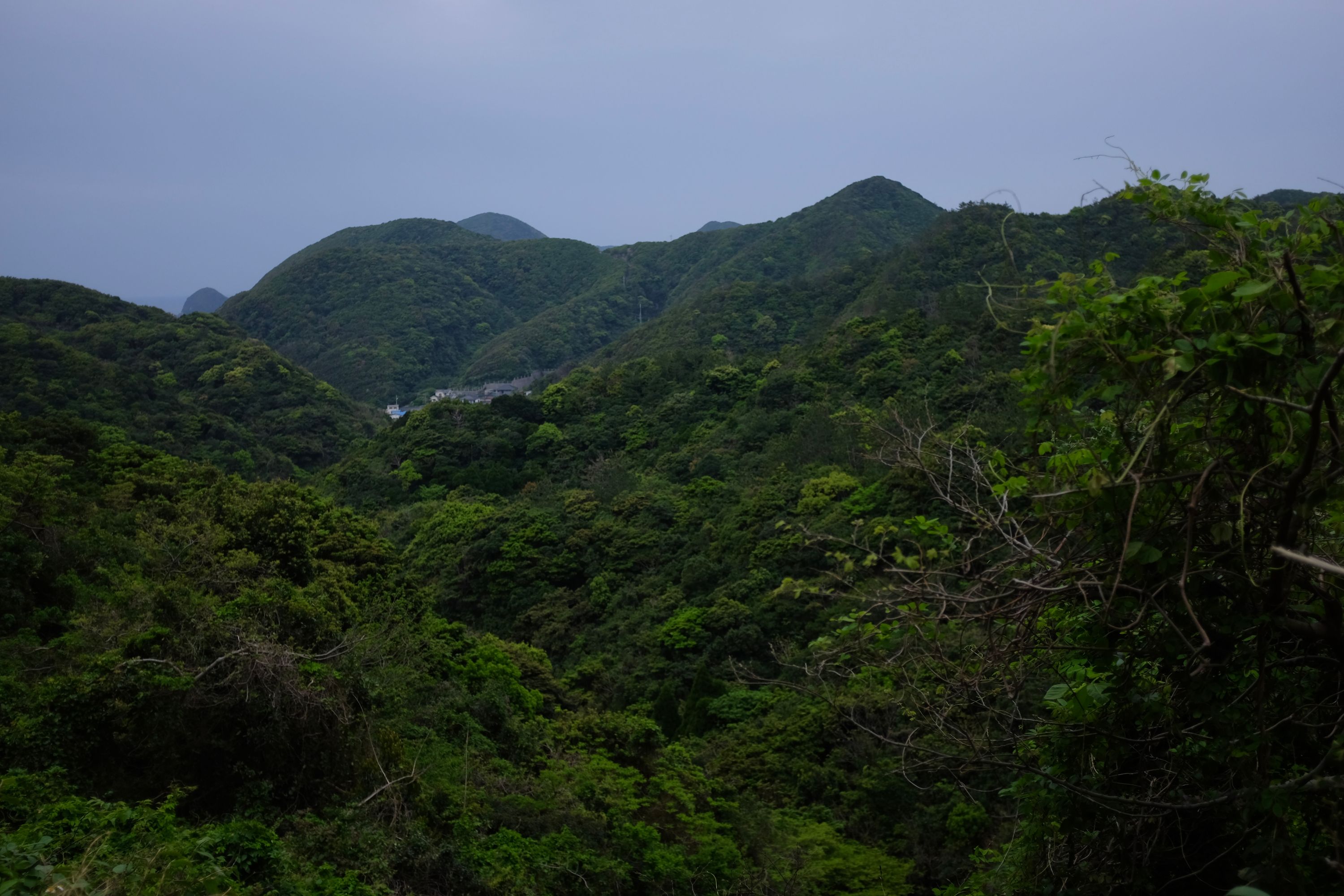 A small village in a valley of hills covered in dense jungle.