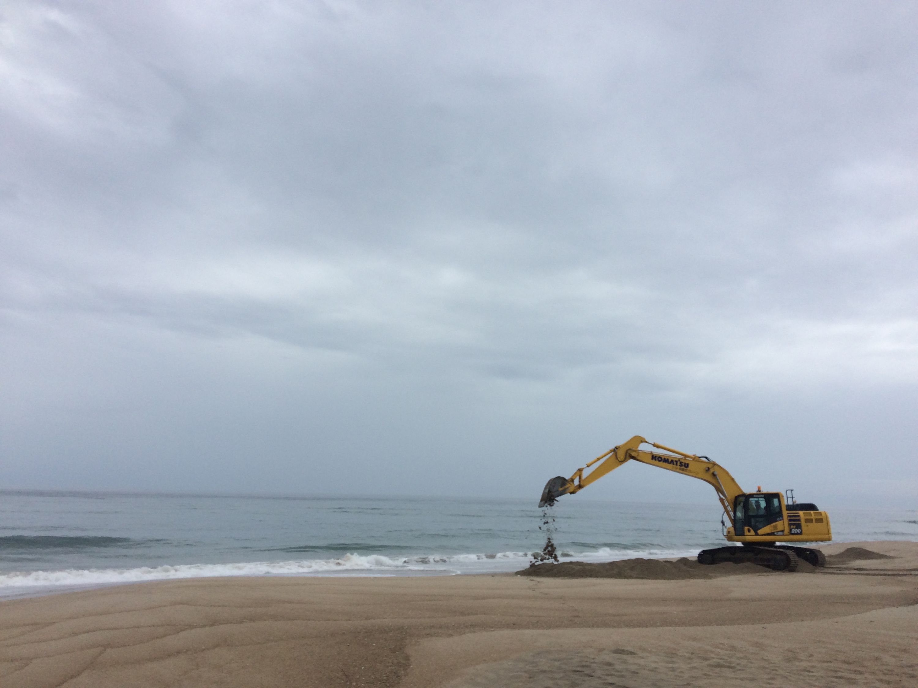 A yellow Komatsu excavator on a beach.