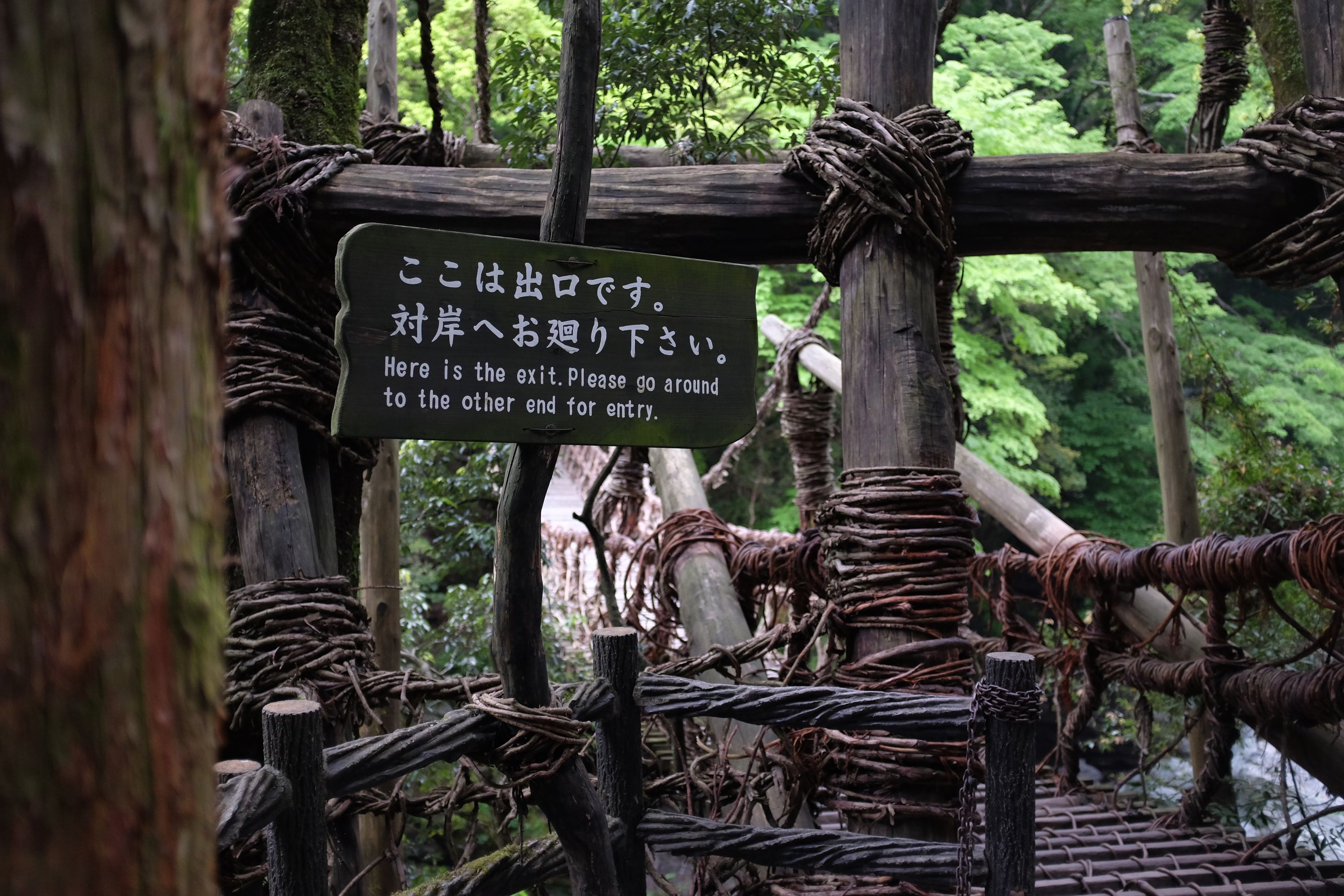 Sign on a vine bridge which says: Here is the exit. Please go around to the other end for entry.