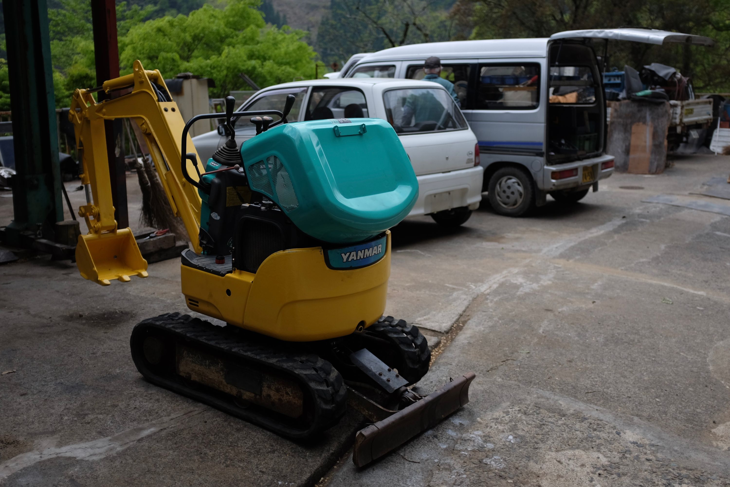 A tiny yellow excavator in a parking lot.