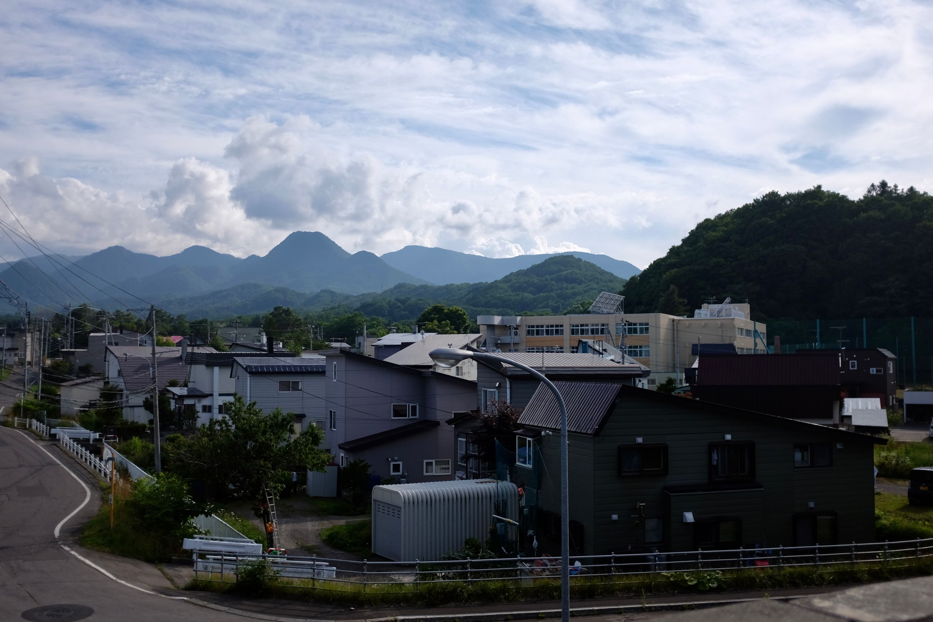 A rugged, mountainous landscape behind a small town in the elbow of a road.