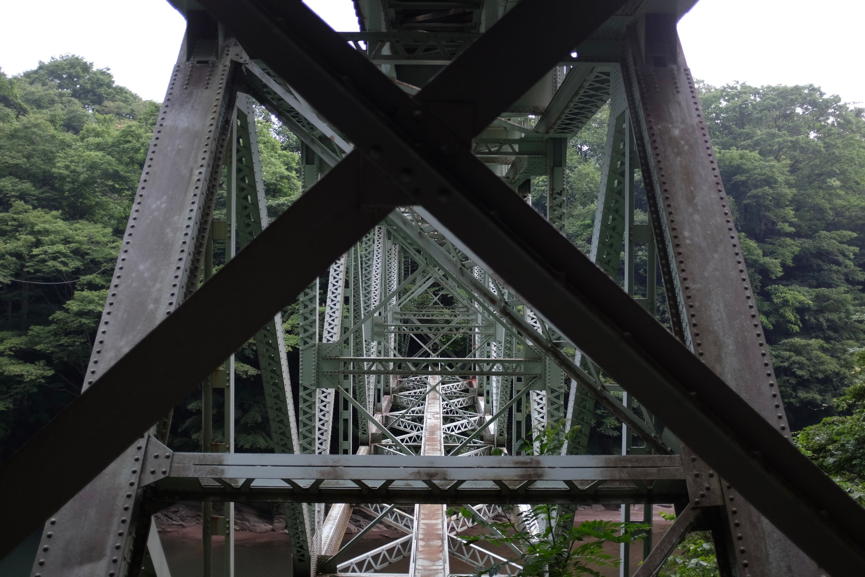 Closeup of the iron girders of a bridge over a river.
