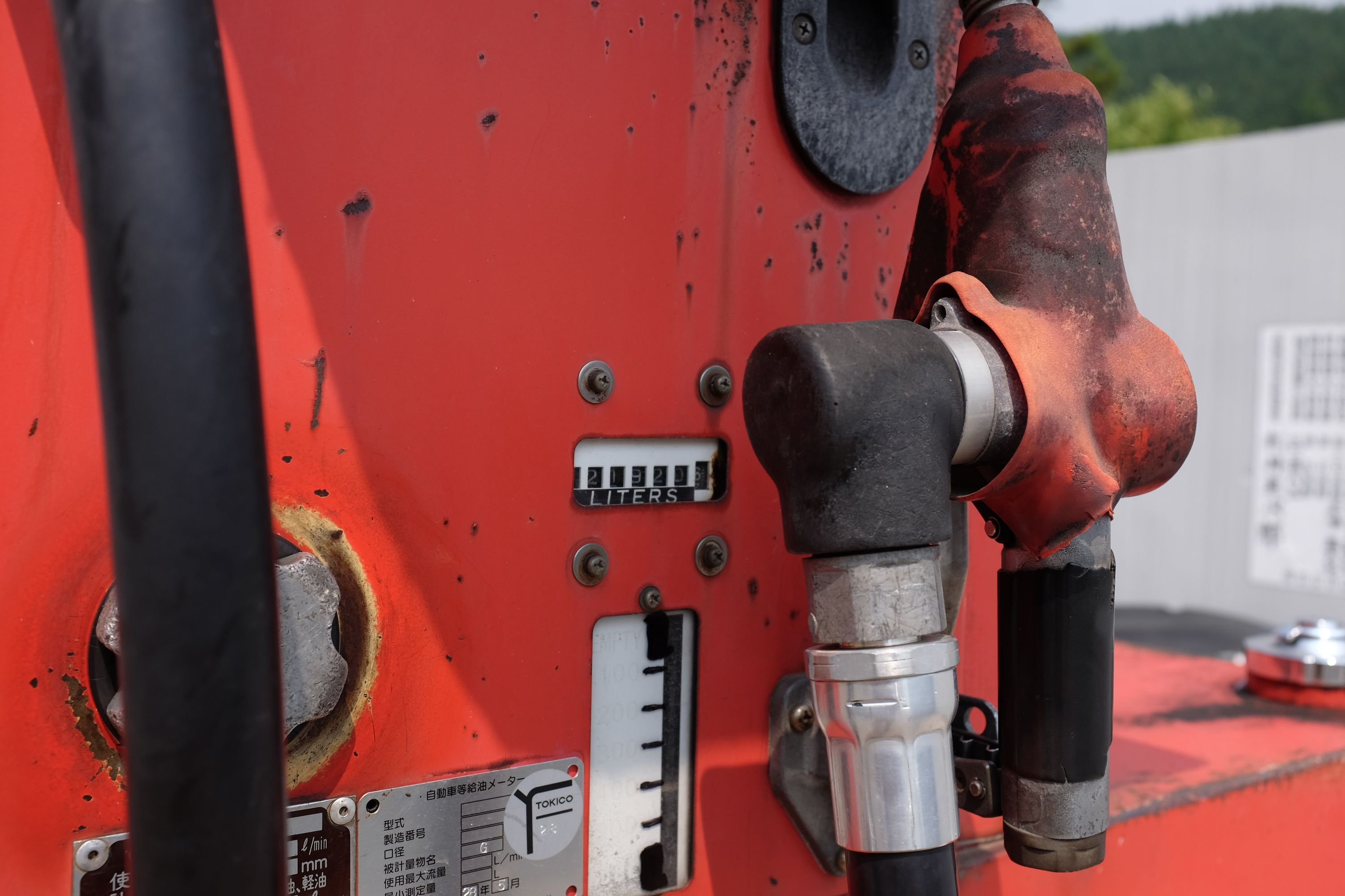 Closeup of an abandoned-looking red petrol pump.