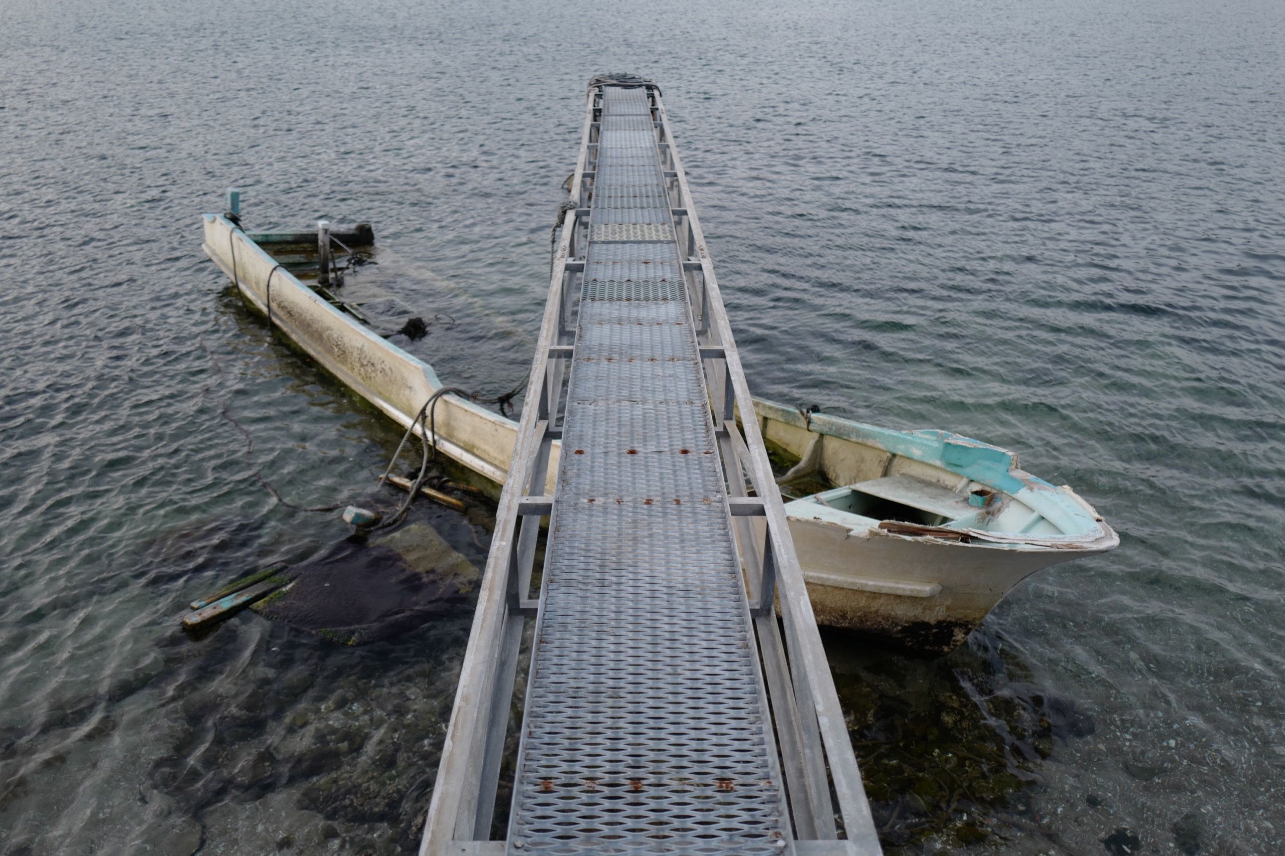 A half-sunk fishing boat under a pier.