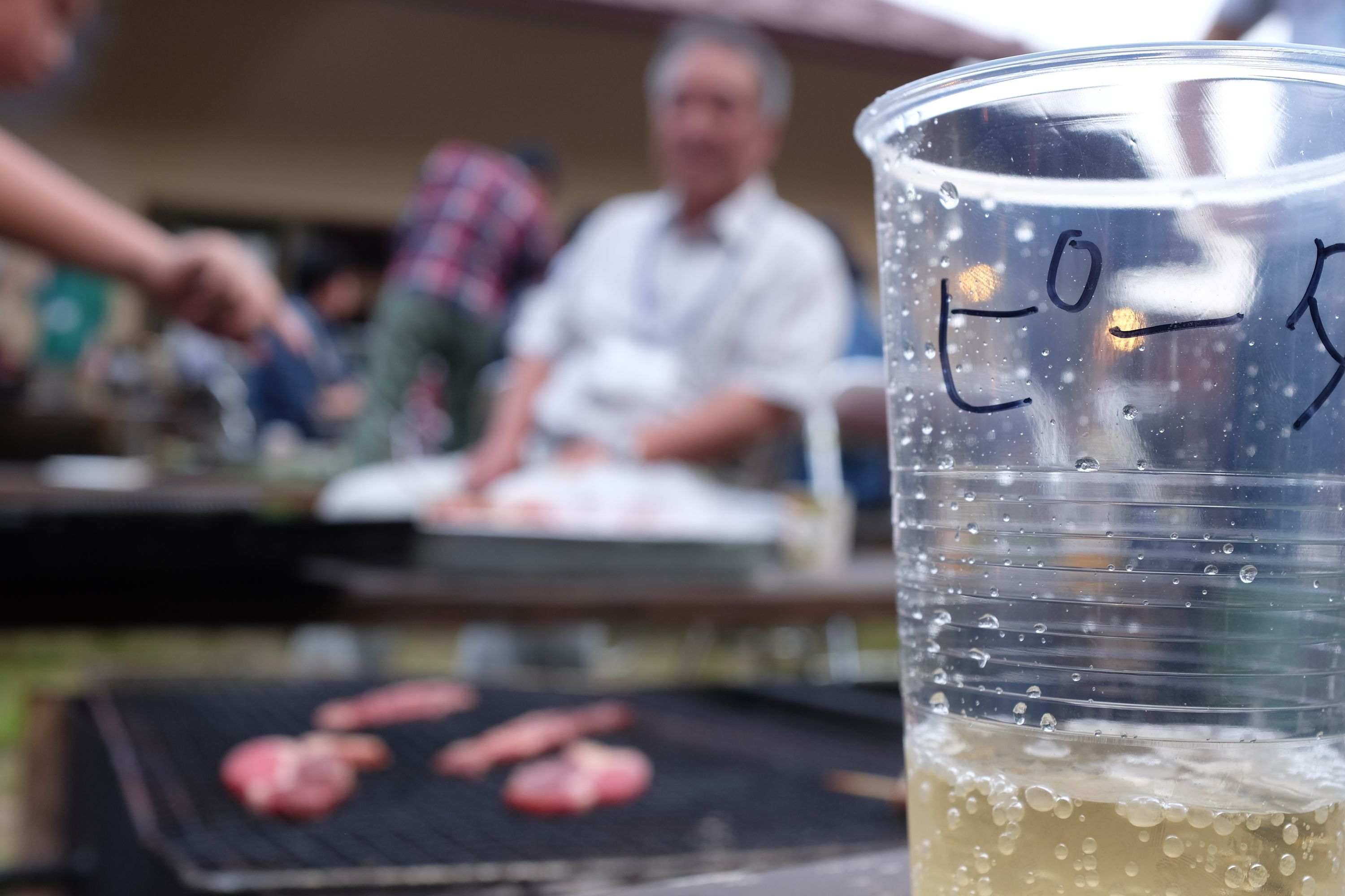 A plastic cup with the author’s name in Japanese, ピーター, written on it in black marker.