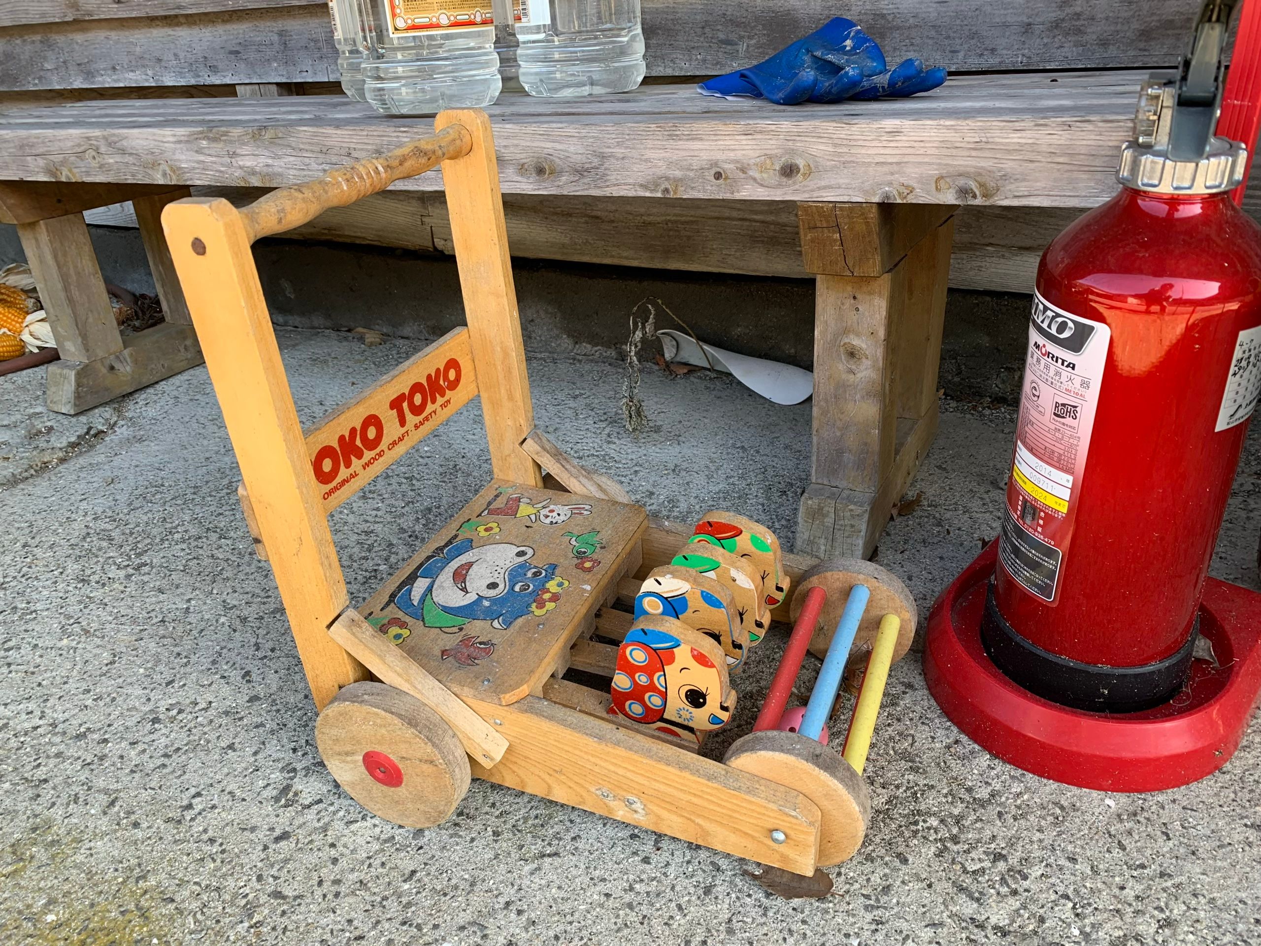 A child’s wooden toy placed next to a red fire extinguisher.