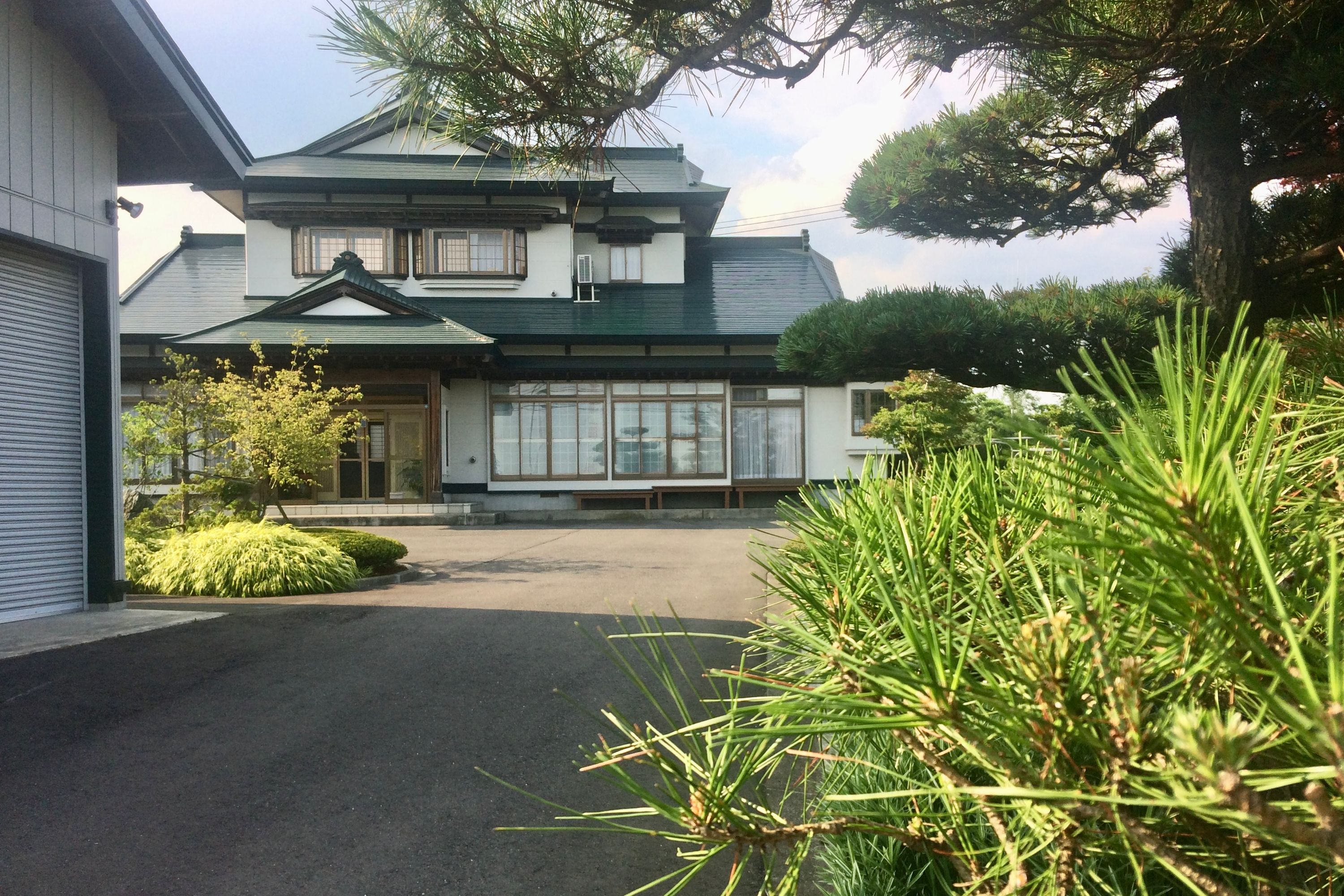 A large, old-fashioned but new house at the end of a driveway.