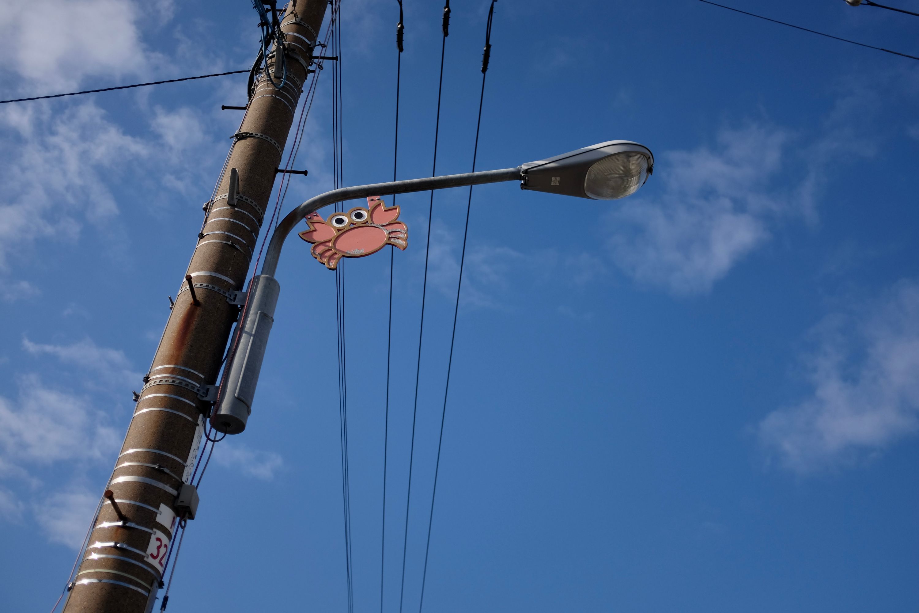 A red cartoon crab balances on a light pole.