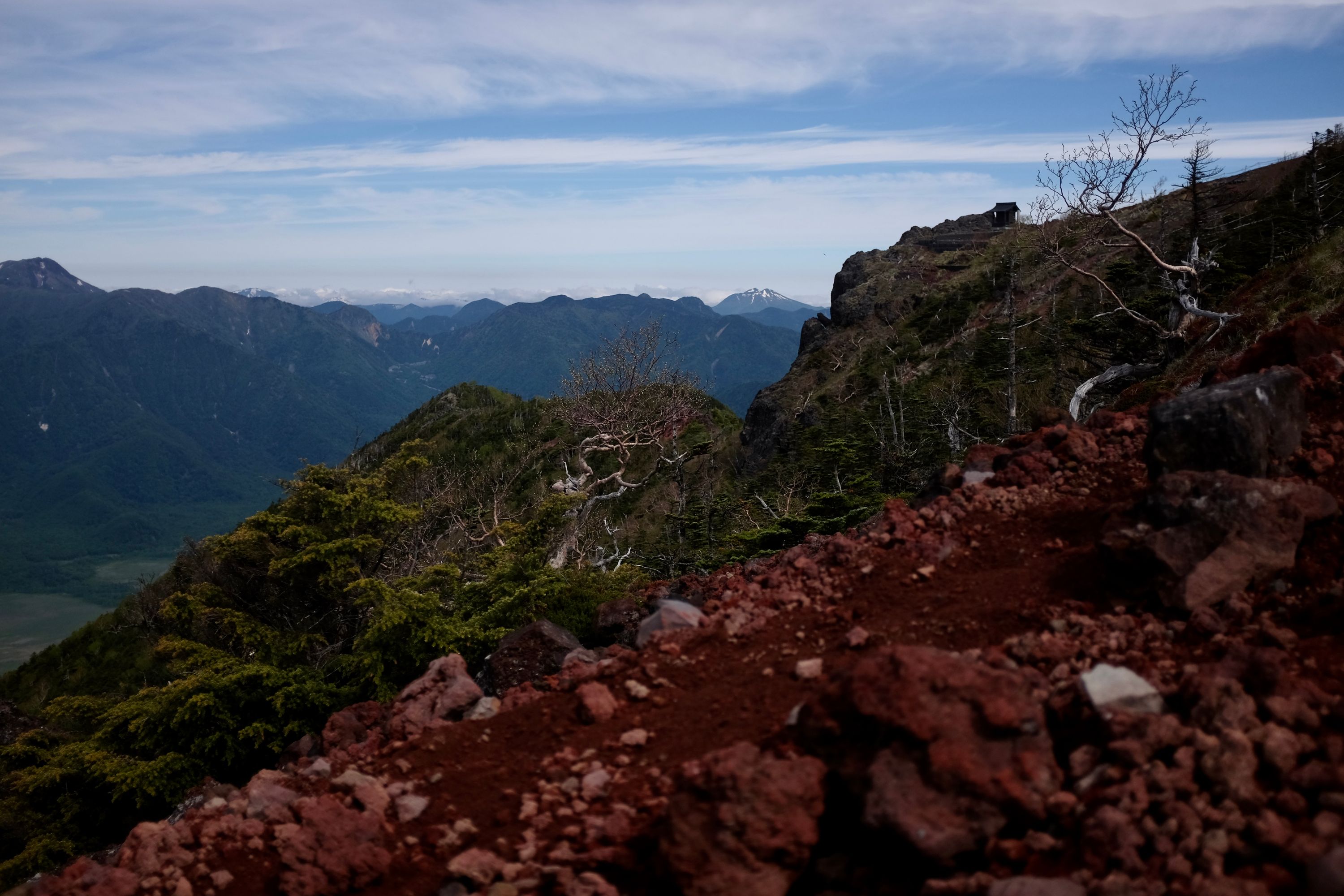 A scree slope on the summit of Mount Nantai, with snow-covered peaks on the horizon.