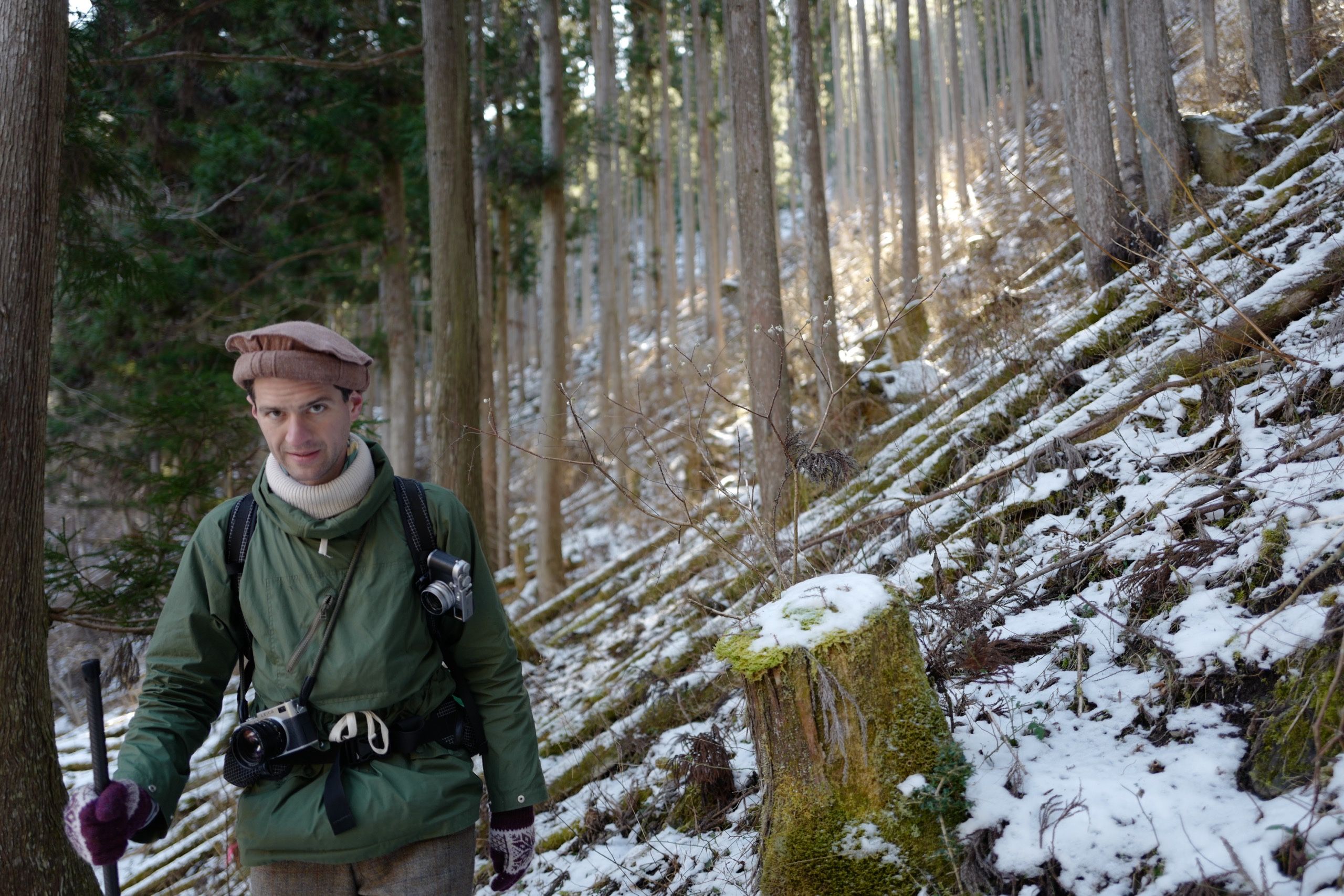 Peter Orosz, in a straw hat and holding his walking stick, stands by the side of the road.