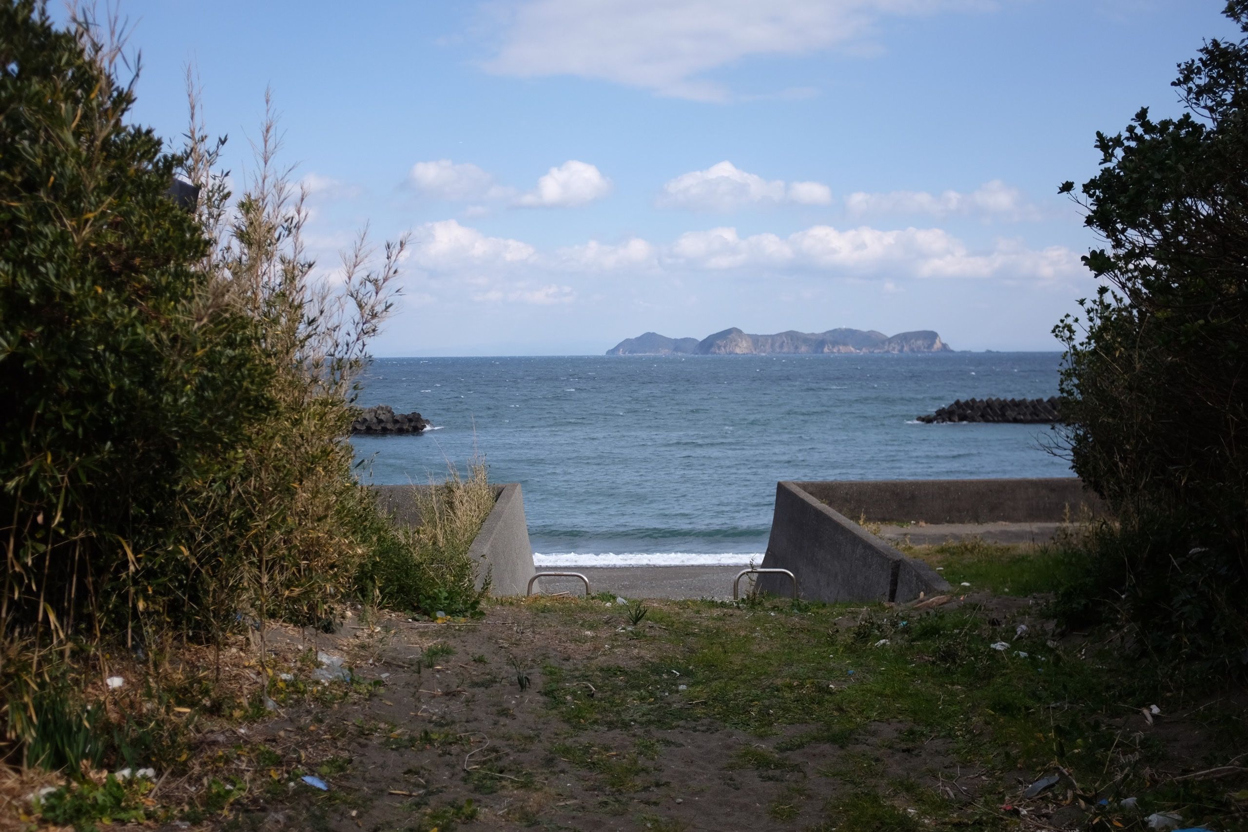 Looking out on a sandy beach and a small island on the horizon.