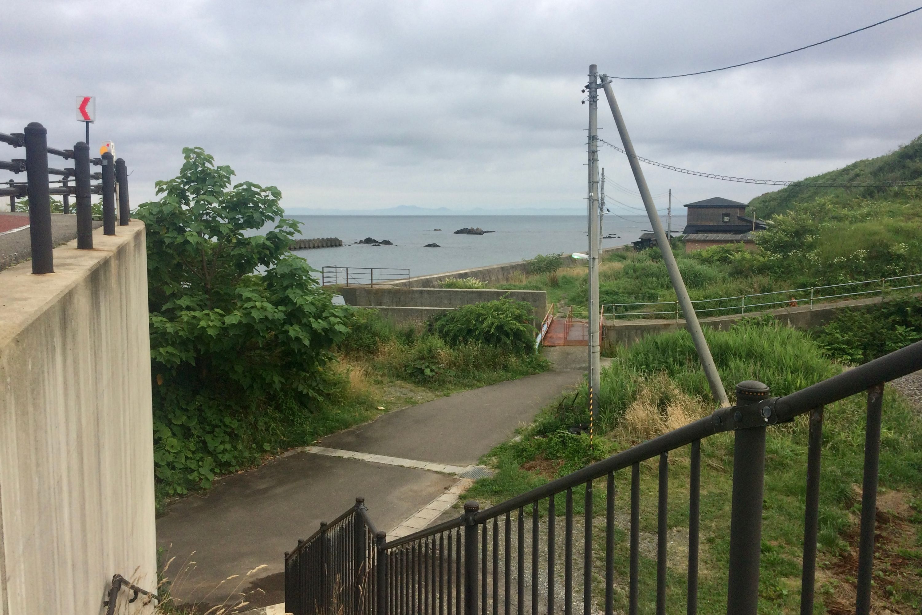 From a set of steps in a seaside village, mountains are visible across the sea.